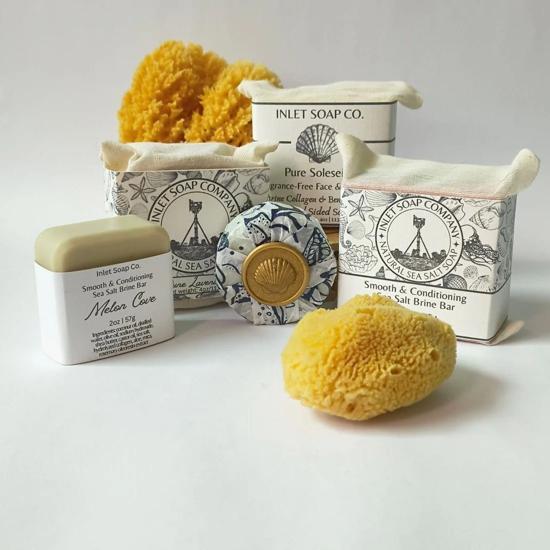 Collection of seashell-themed soap and bath products, including bars, sponges, and packaging with nautical designs.