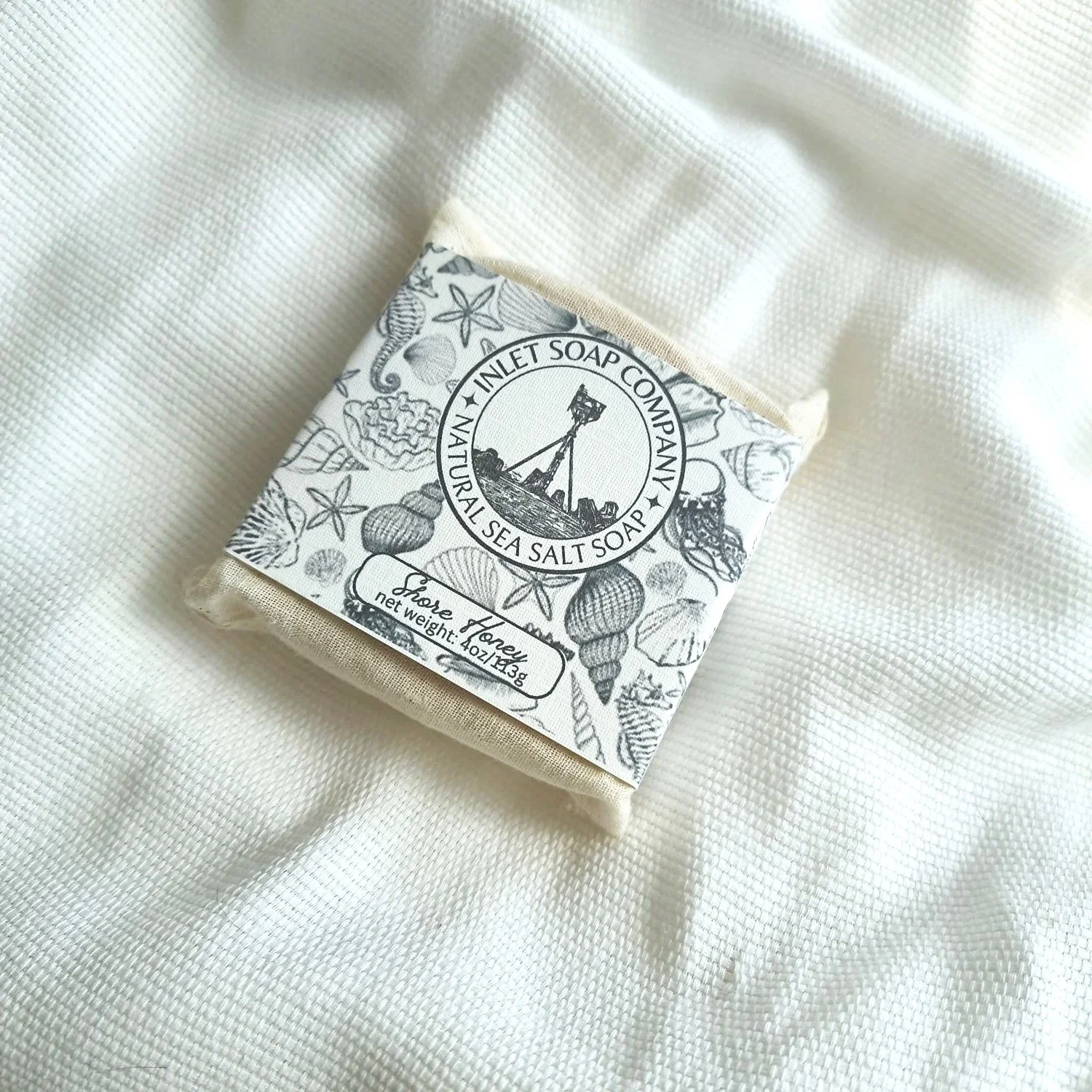 Inlet Soap Co. Shore Honey sea salt soap bar in a reusable muslin bag, recyclable cardstock sleeve with logo.