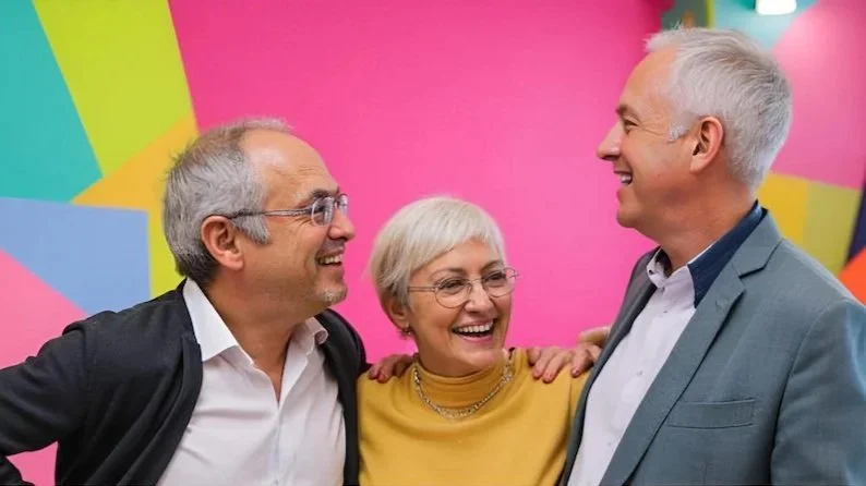 Three smiling middle-aged people, two men and one woman, having an engaging conversation at work that strengthens their relationships and results.