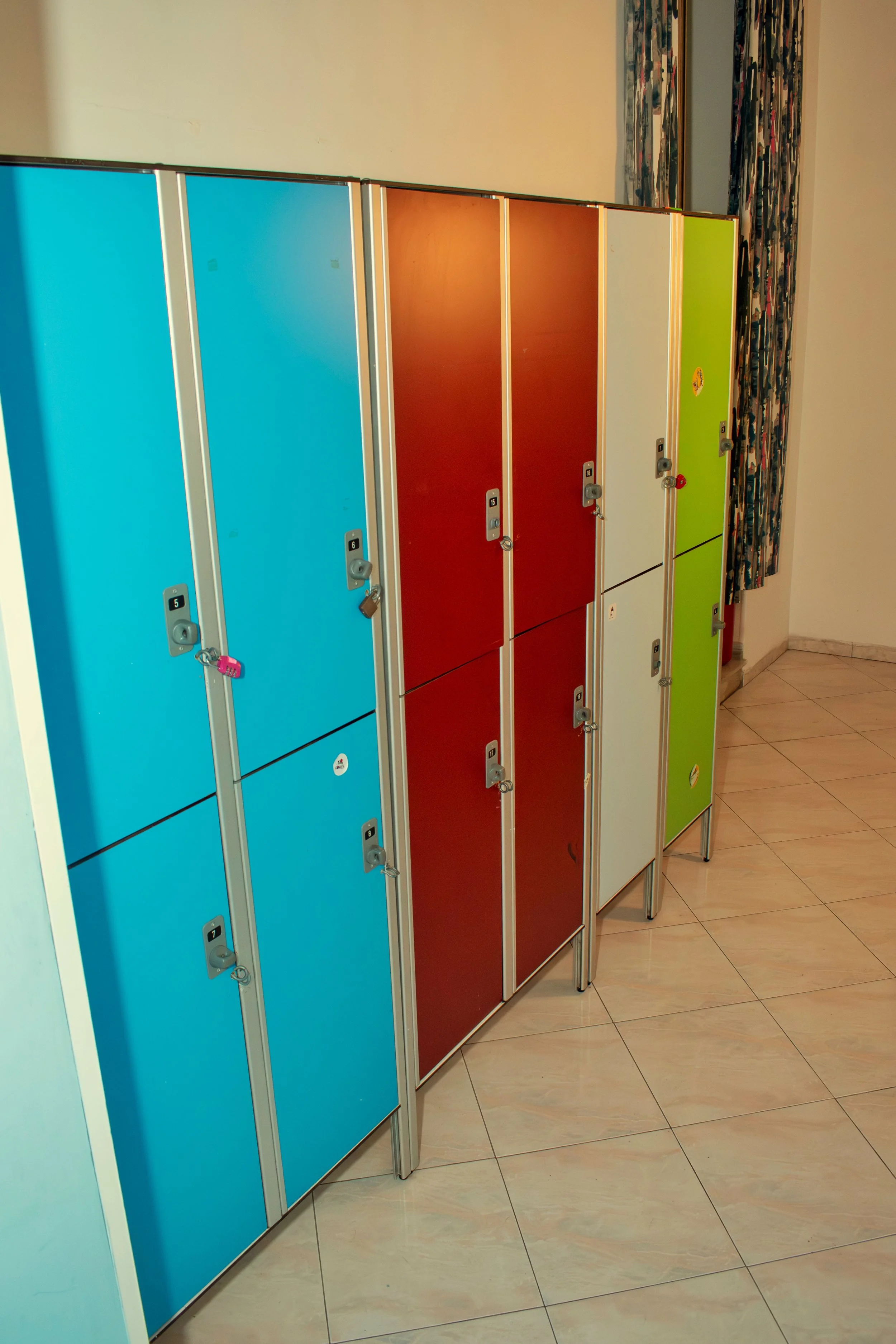 Colorful school lockers, blue, red, white, and green, in a corridor.