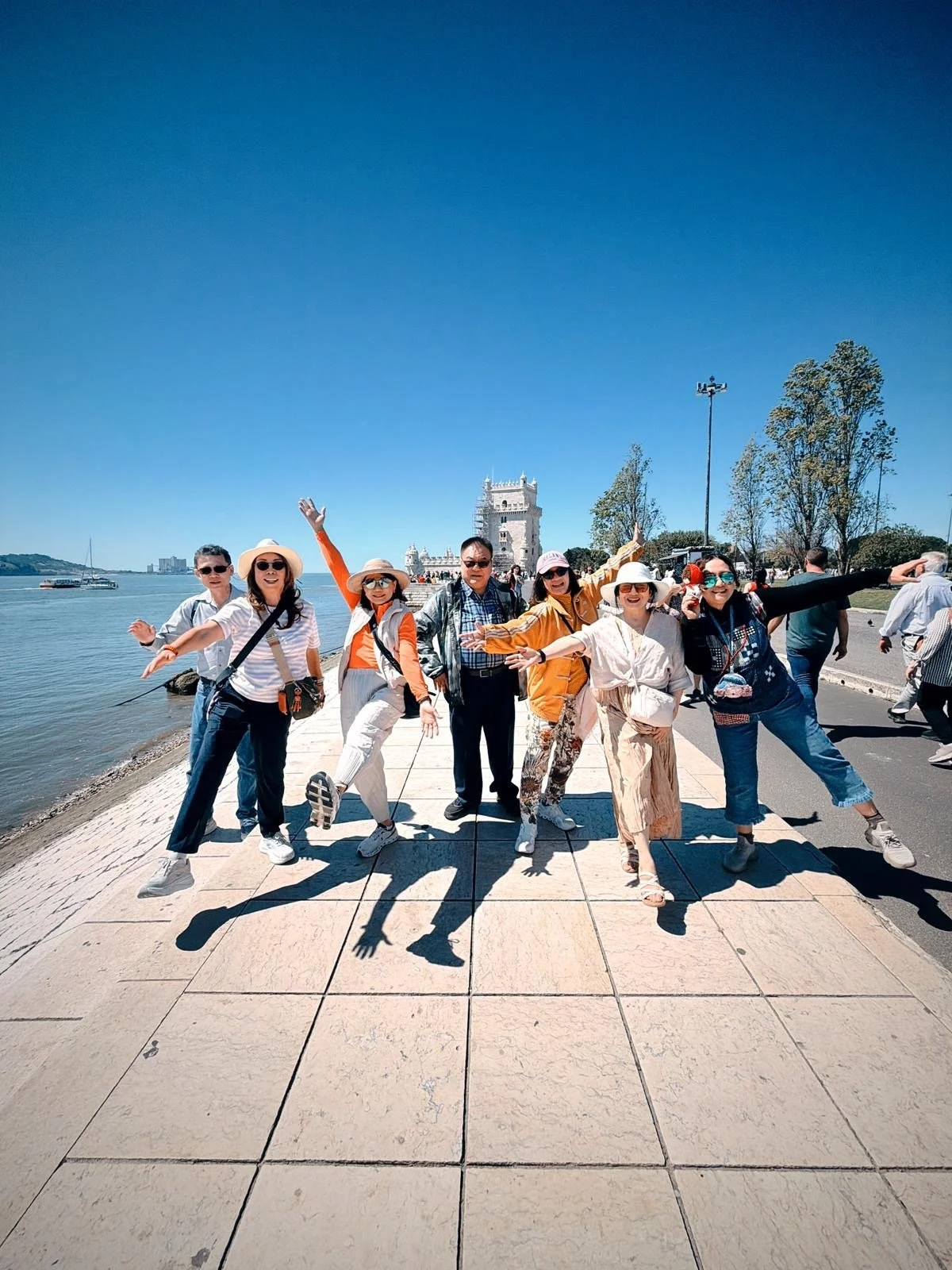 A group of friends in front of Belem Tower in Lisboa, Portugal, next to the river Tagus.