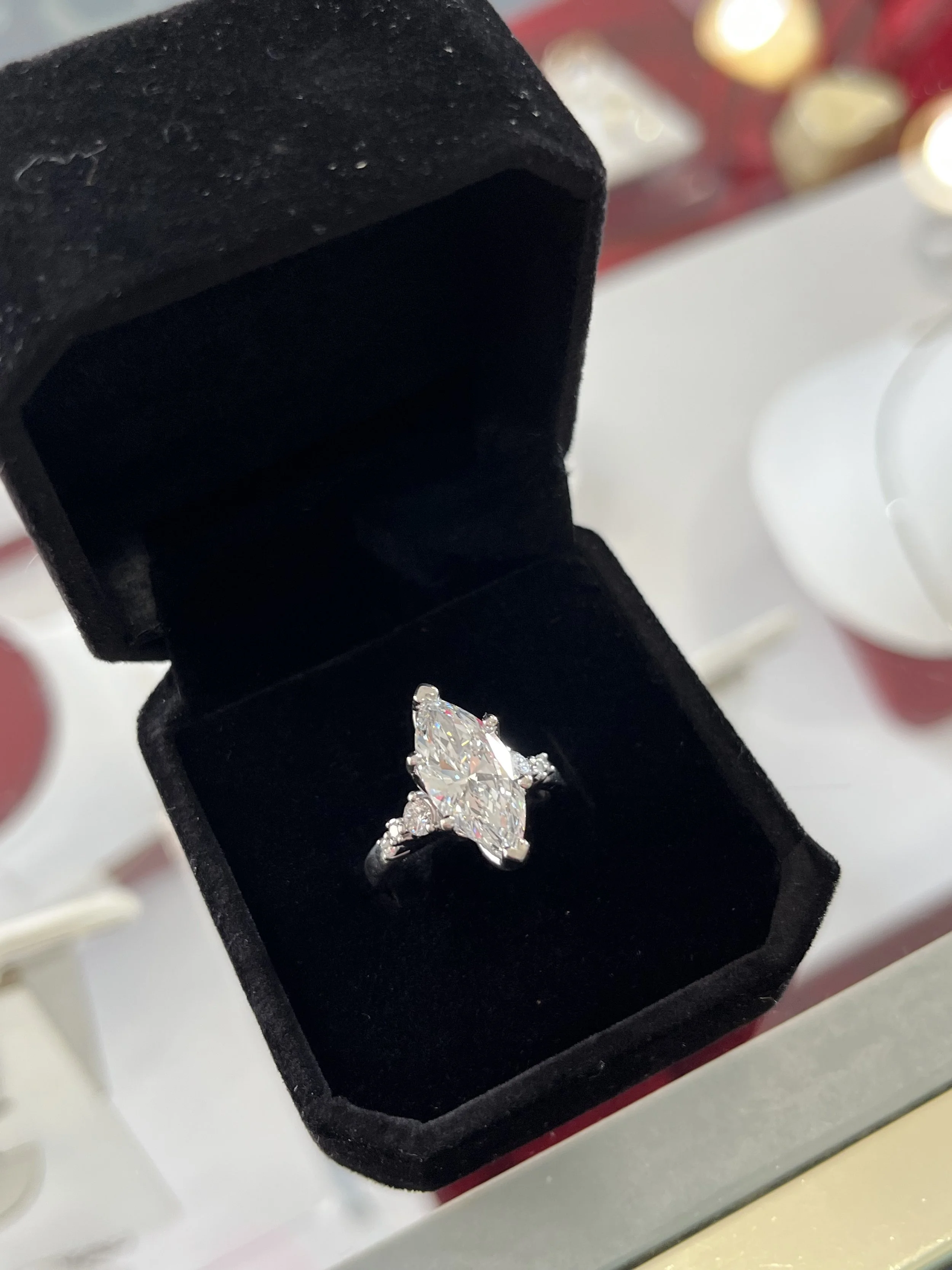 A custom engagement ring by TSC Jewelry. This stunning marquise diamond ring features a white gold setting and round diamond accents