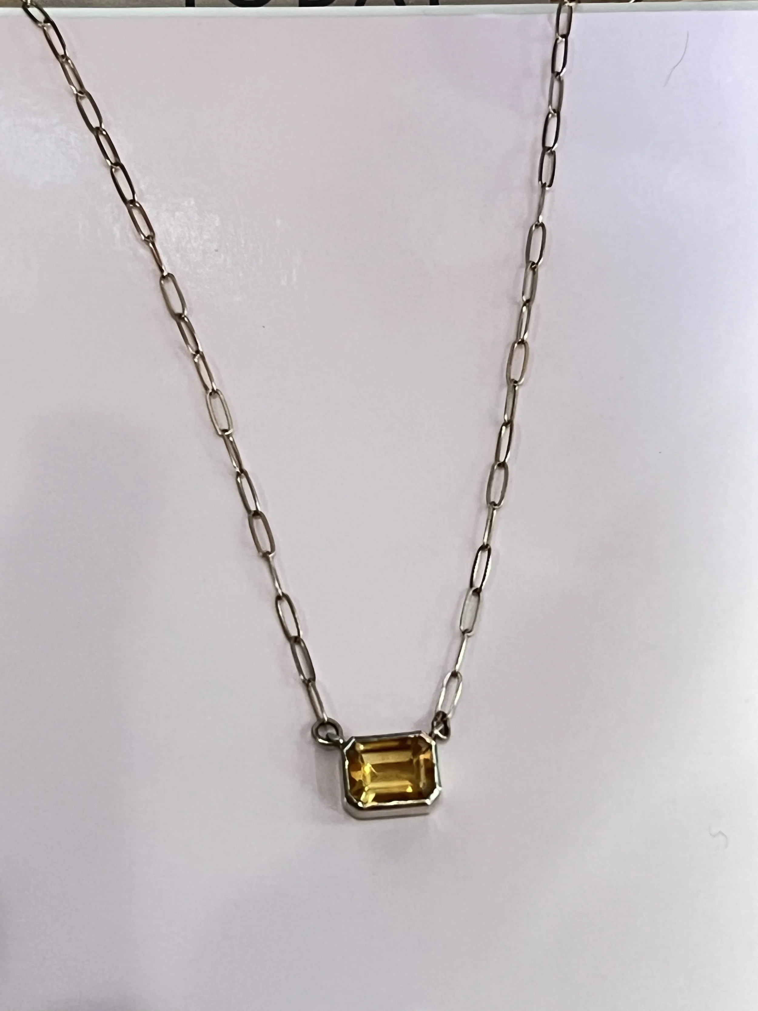 Silver chain necklace with a yellow rectangular gemstone pendant.