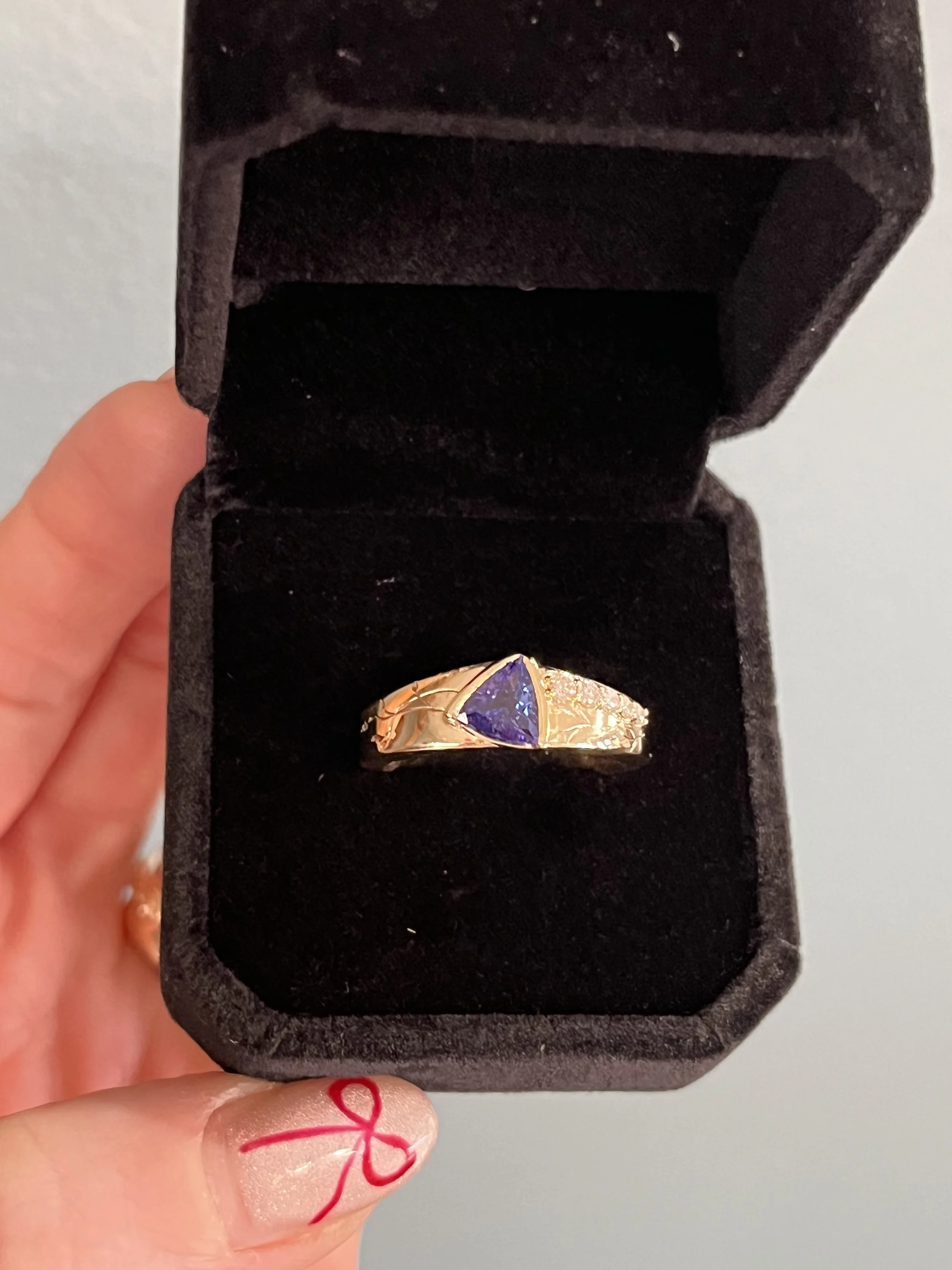 A custom made tanzanite ring featuring diamond accents and nature inspired engraving by TSC Jewelry