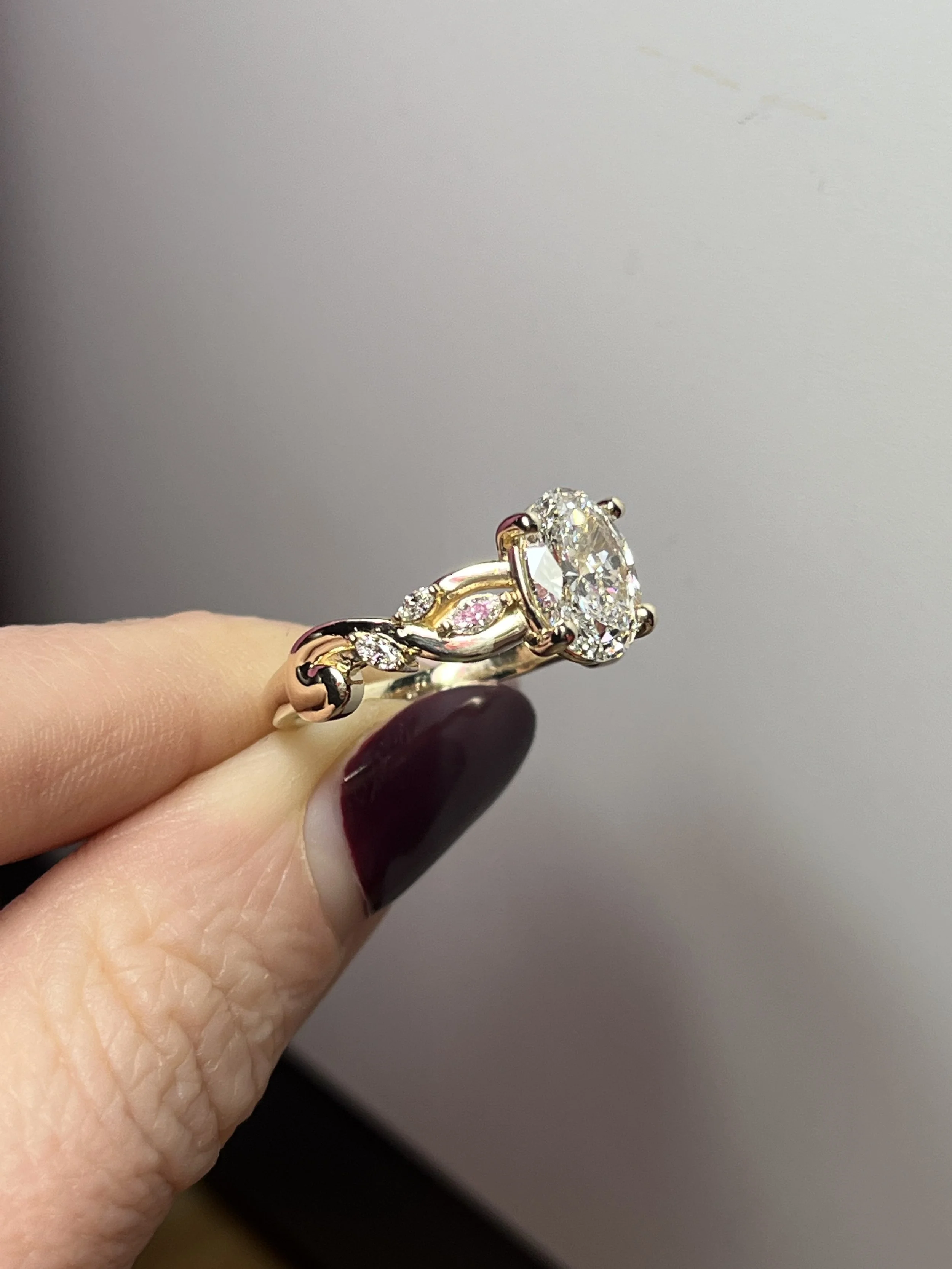 A gorgeous oval engagement ring with a vine-inspired diamond accented band, custom made by TSC Jewelry