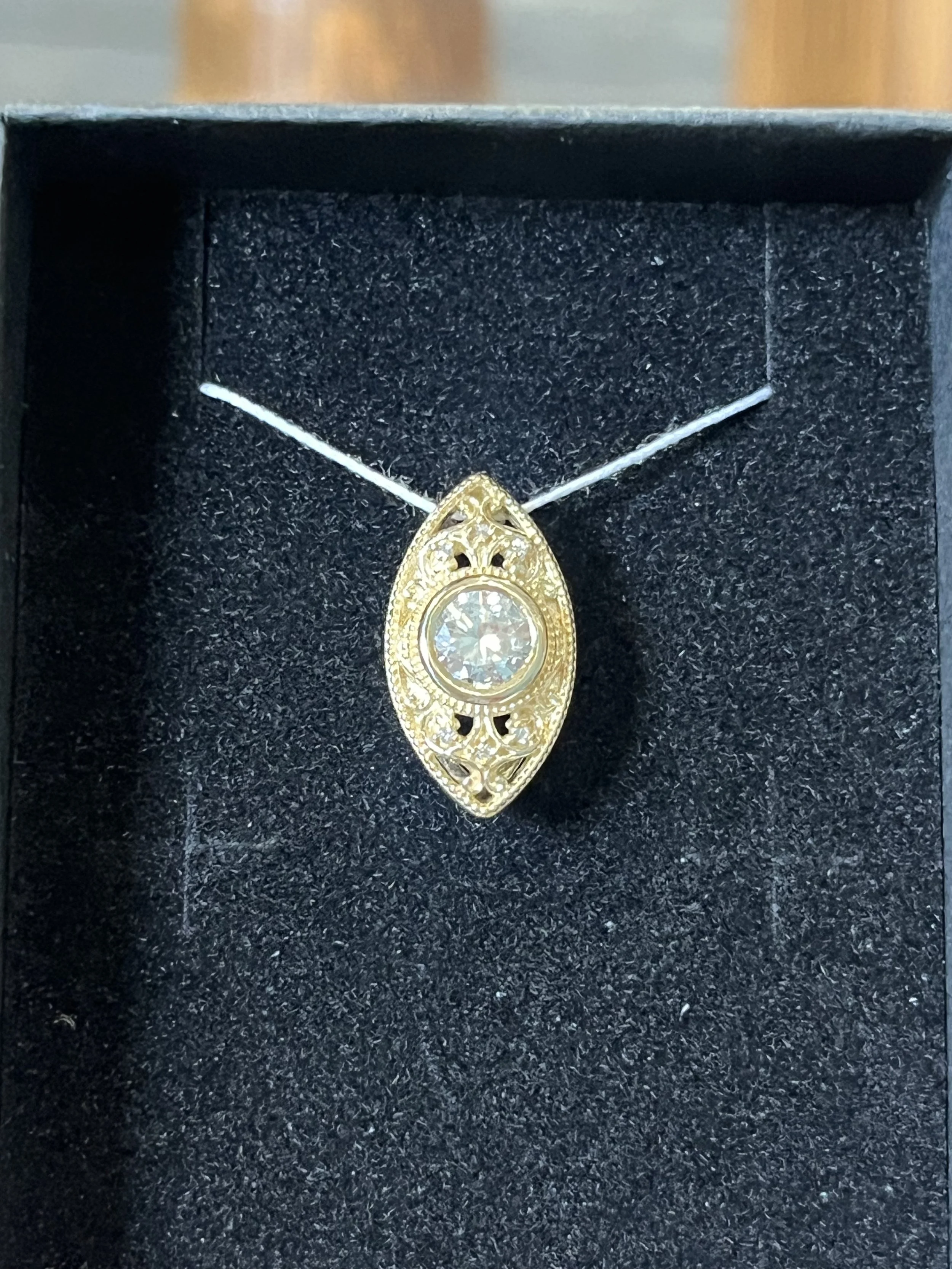 A custom pendant by TSC Jewelry. This vintage inspired pendant features a gorgeous rounddiamond center stone