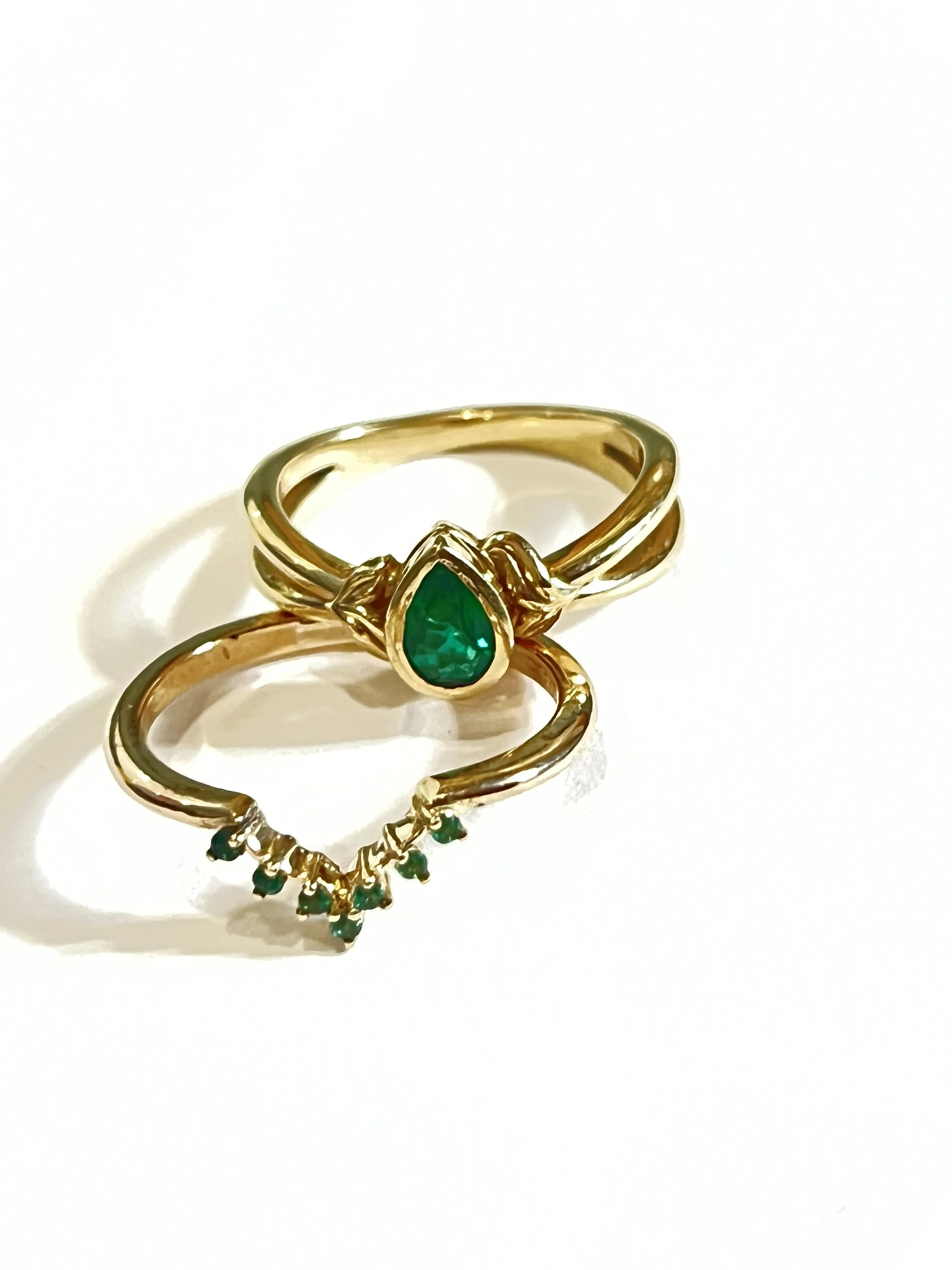 A custom made wedding set by TSC Jewelry. This set features a stunning bezel set pear shape emerald and matching emerald contour wedding band