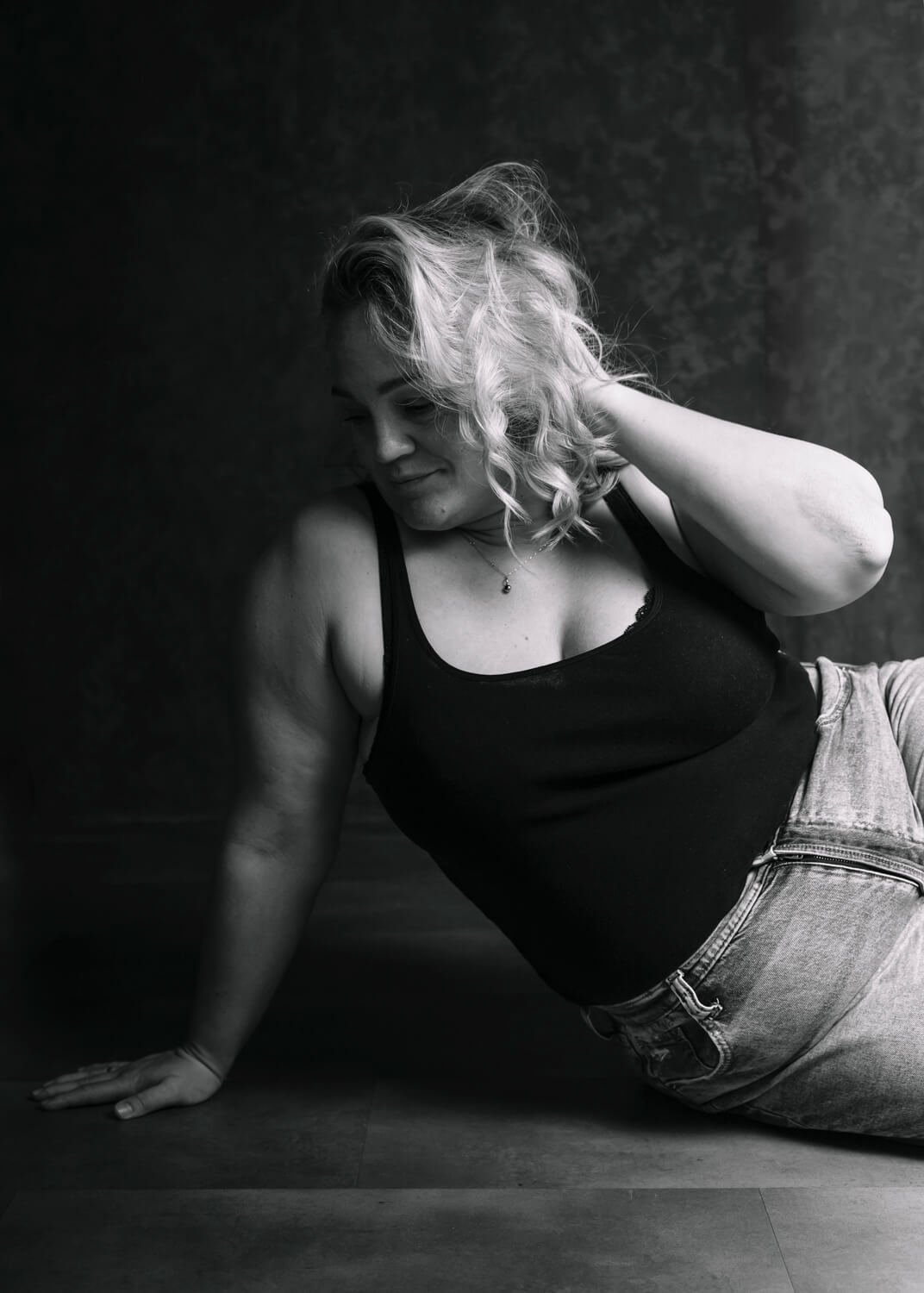 woman lying on side with hand tousling hair in black and white photo