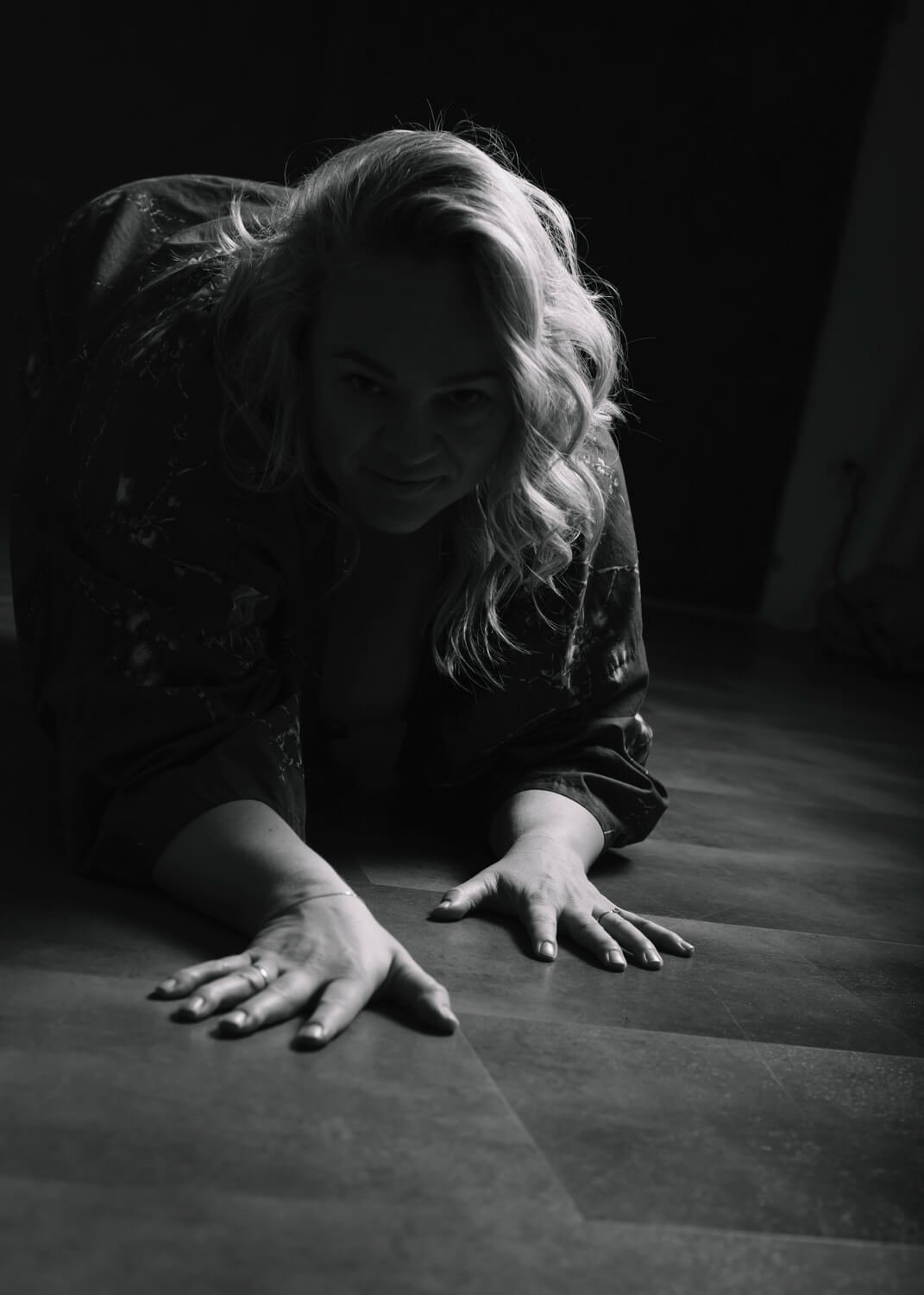 silhouette image of woman crawling toward camera in black and white shot