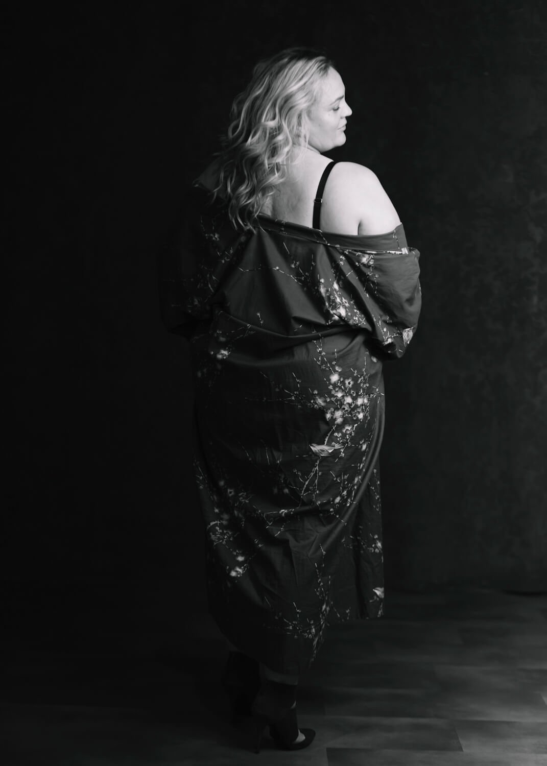 woman standing with back to camera with kimono coming off her shoulder in black and white photo