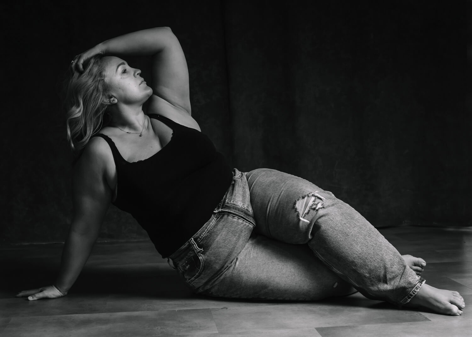 beautiful curvy woman lying on side with hand in hair in black and white photo