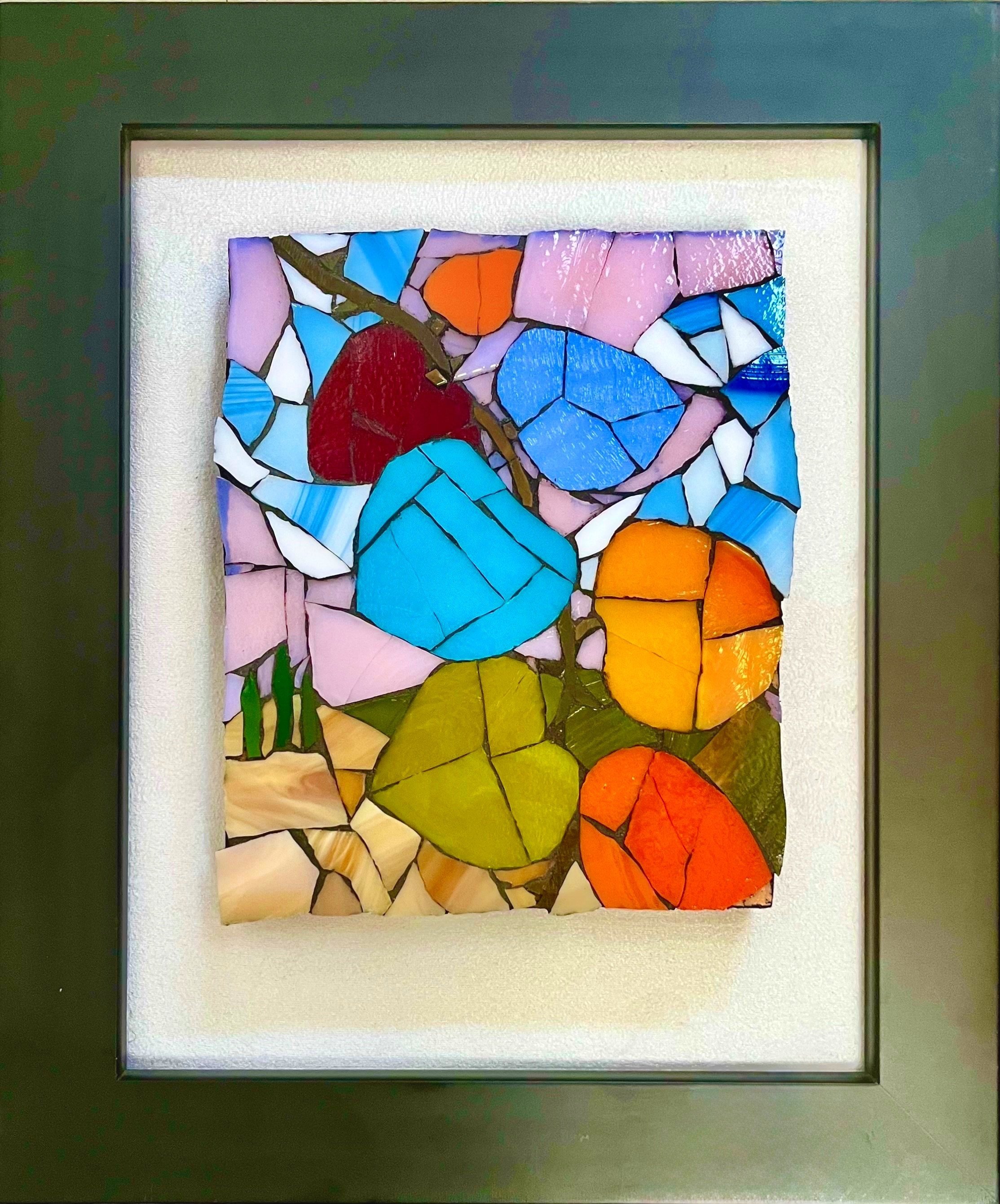 Glass mosaic of colorful abstract leaves or pods in shades of blue, red, orange, green, and purple, set against a soft pink and beige background