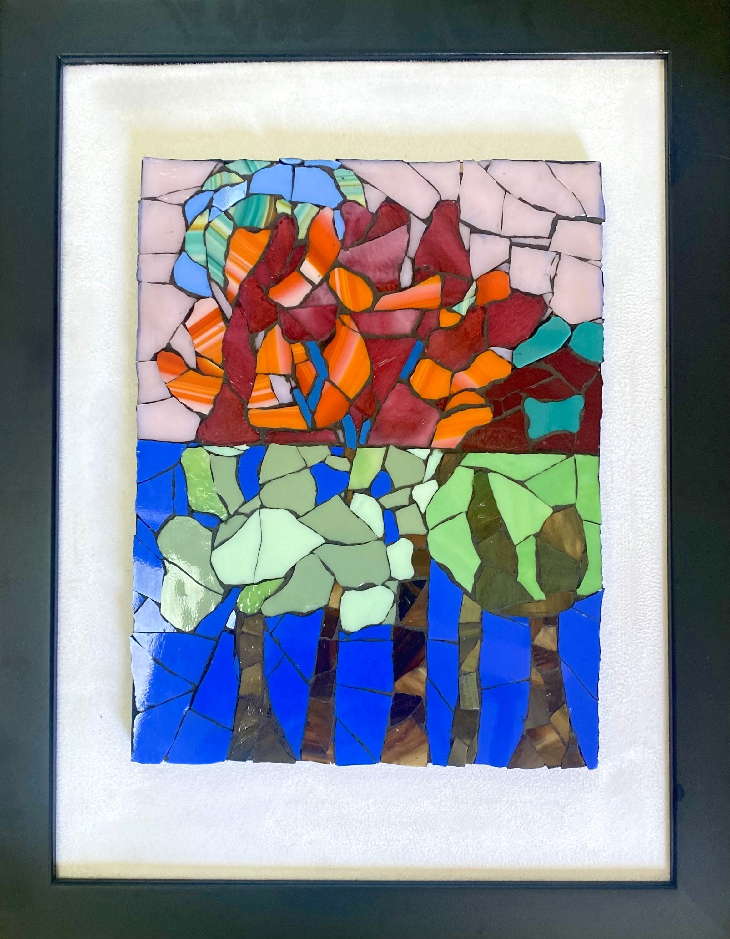 Glass mosaic of three trees with green canopies against a vivid blue background, with a burst of red, orange, and multicolored abstract shapes above them