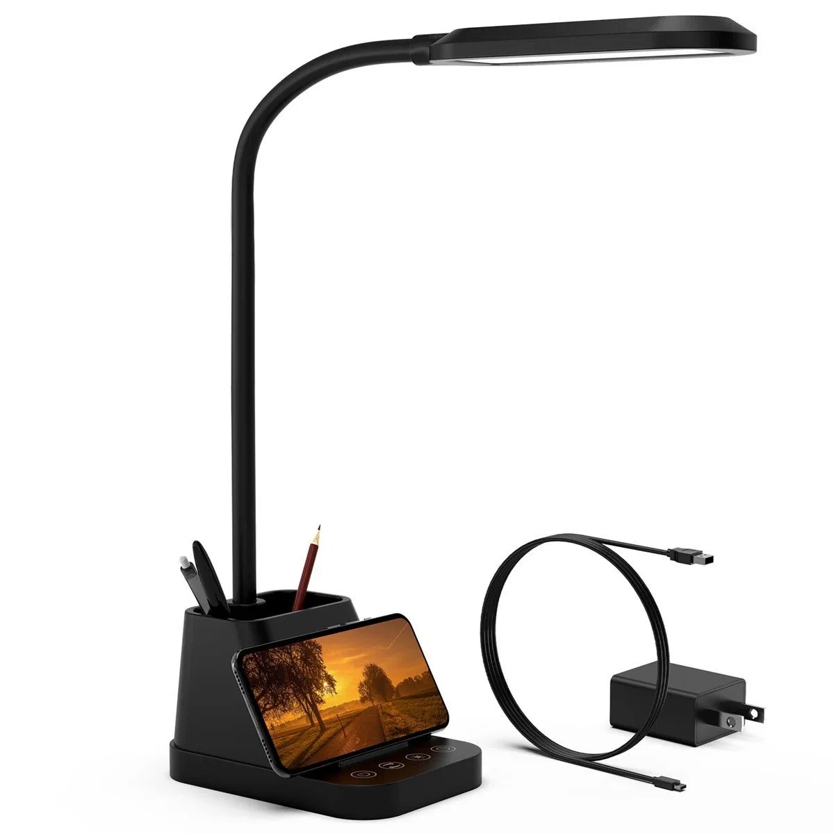 A black Wayfair Desk Lamp with a flexible gooseneck, a built-in phone holder with a phone displaying a sunset, and pen organizer section. A charging cable and power adapter are visible next to it.