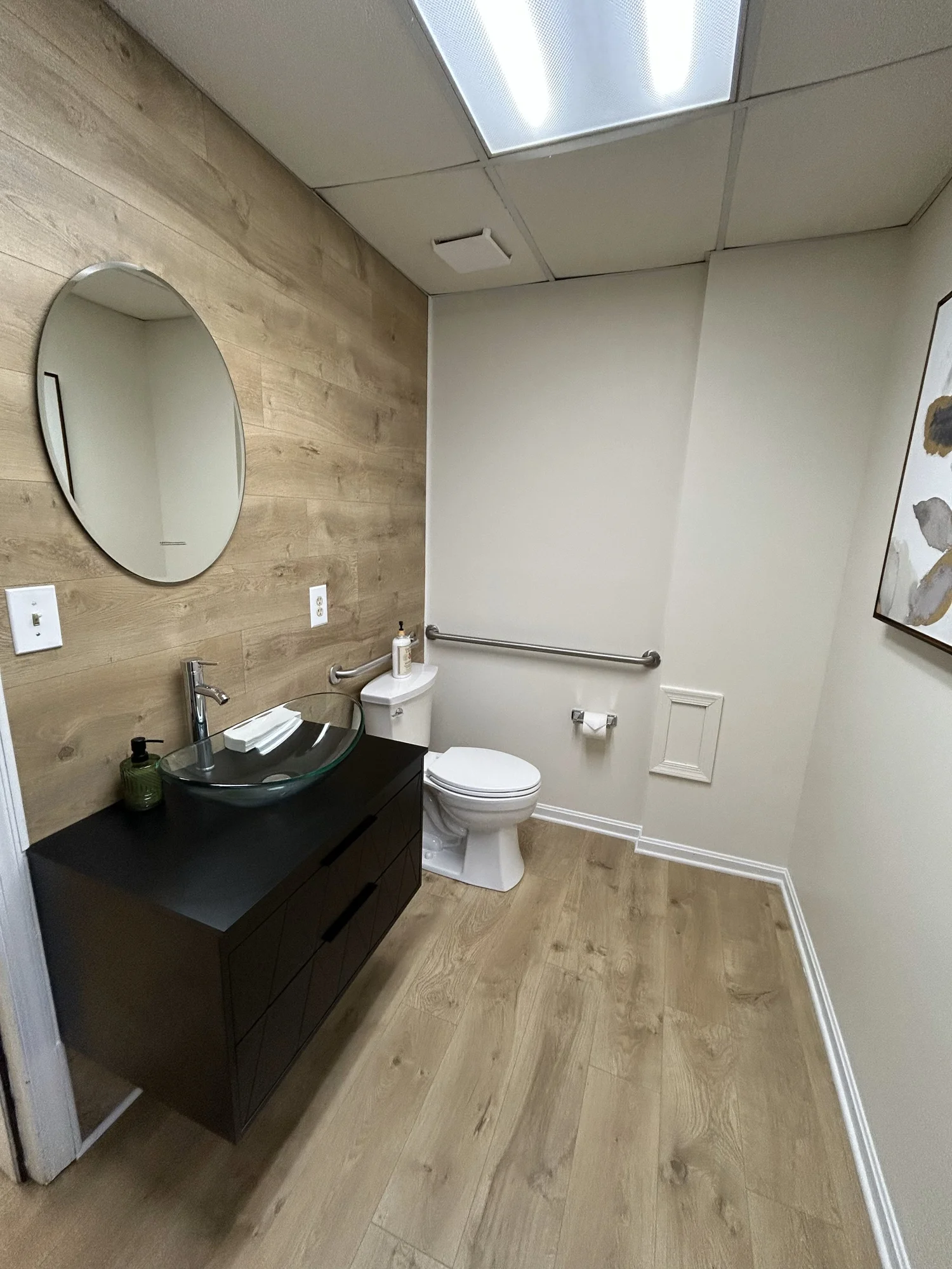 Restroom with vessel sink, wood accent wall and grab bars