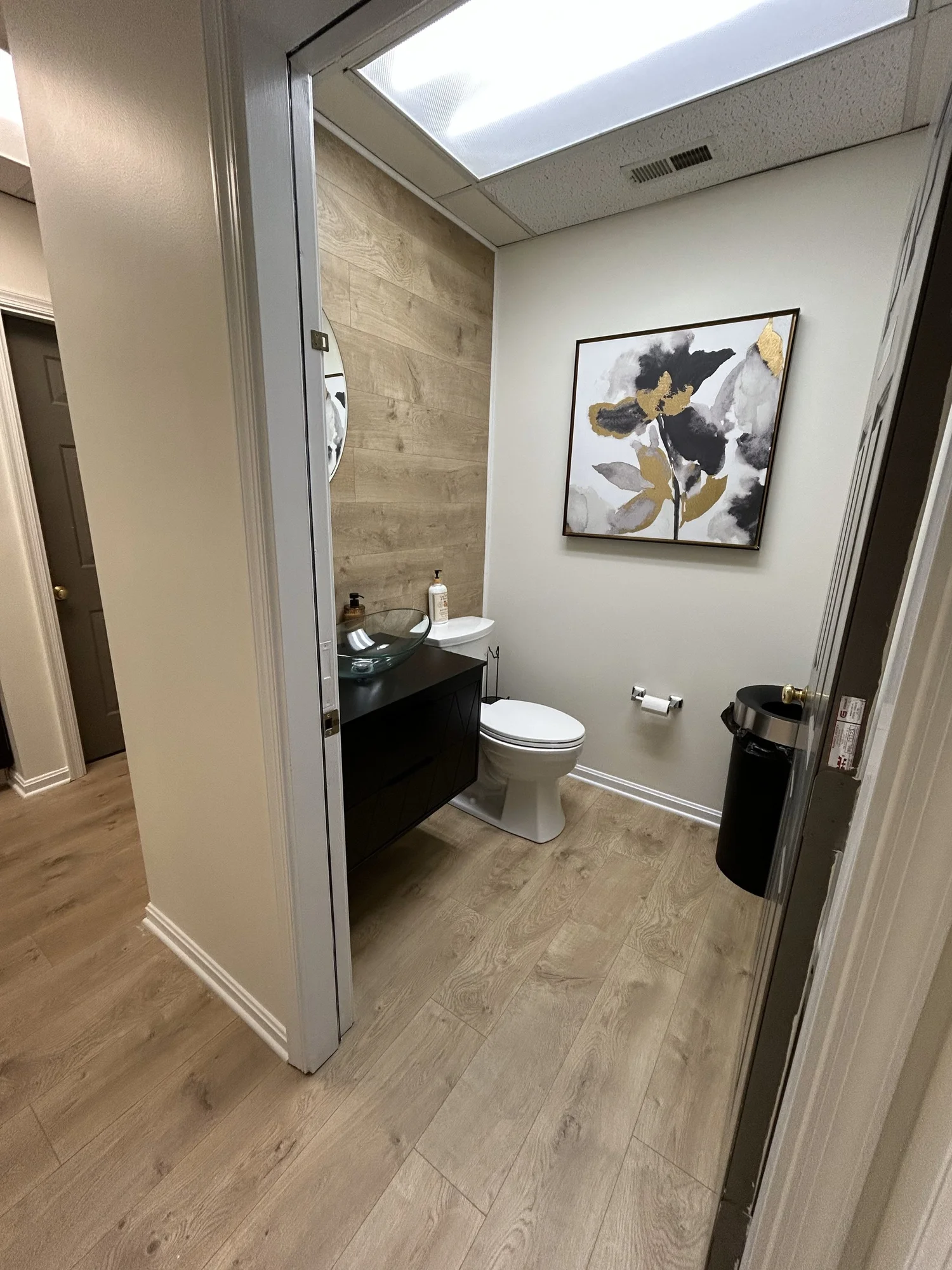 Restroom with framed floral artwork and wood accent wall