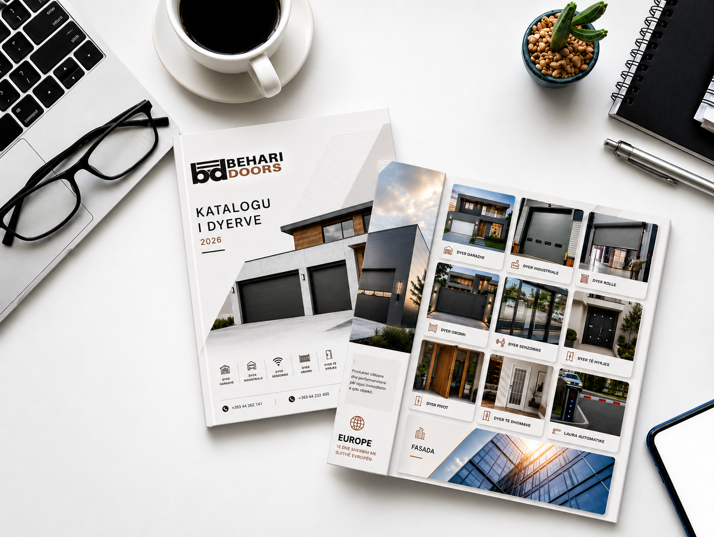 Overhead view of a Behari Doors catalog with a laptop, eyeglasses, coffee cup, succulent, pen, and notebook on a white desk. The catalog features images of garage doors and text in a foreign language.