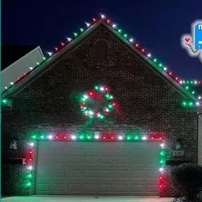 A house with brick exterior decorated with colorful Christmas lights, including a wreath and a section above the garage illuminated with red, green, and white lights.