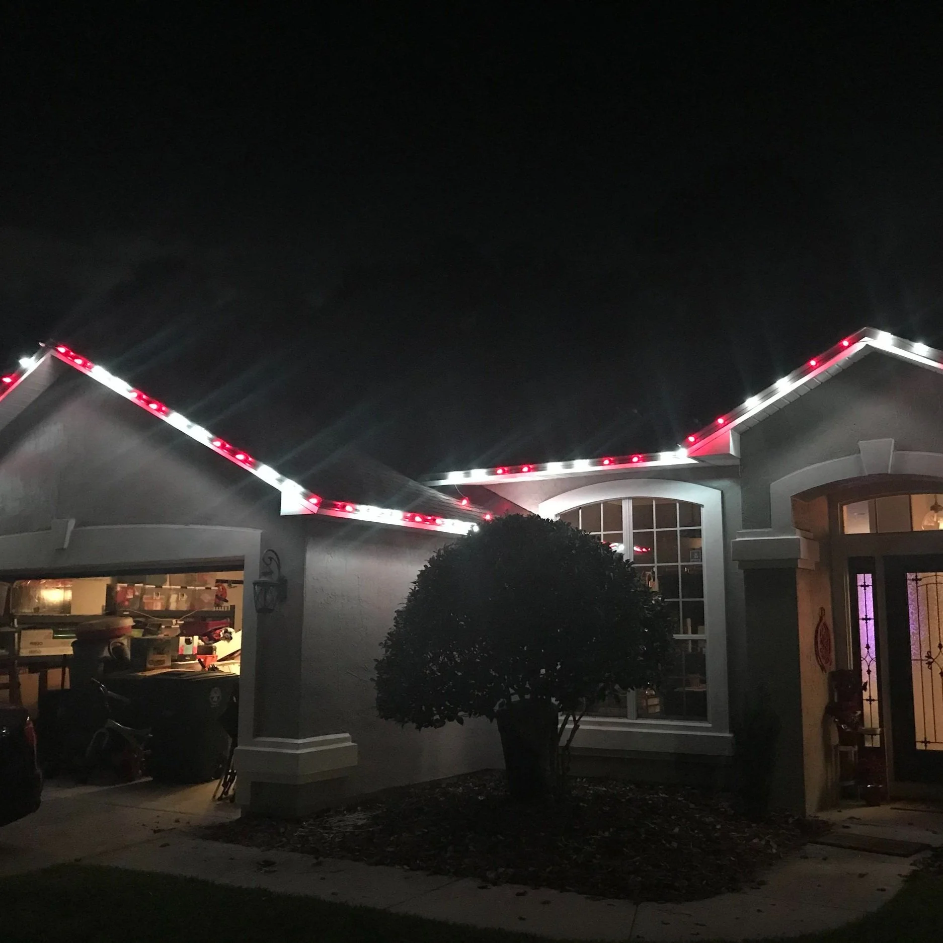 Nighttime view of a house with Christmas lights outlining the roof.