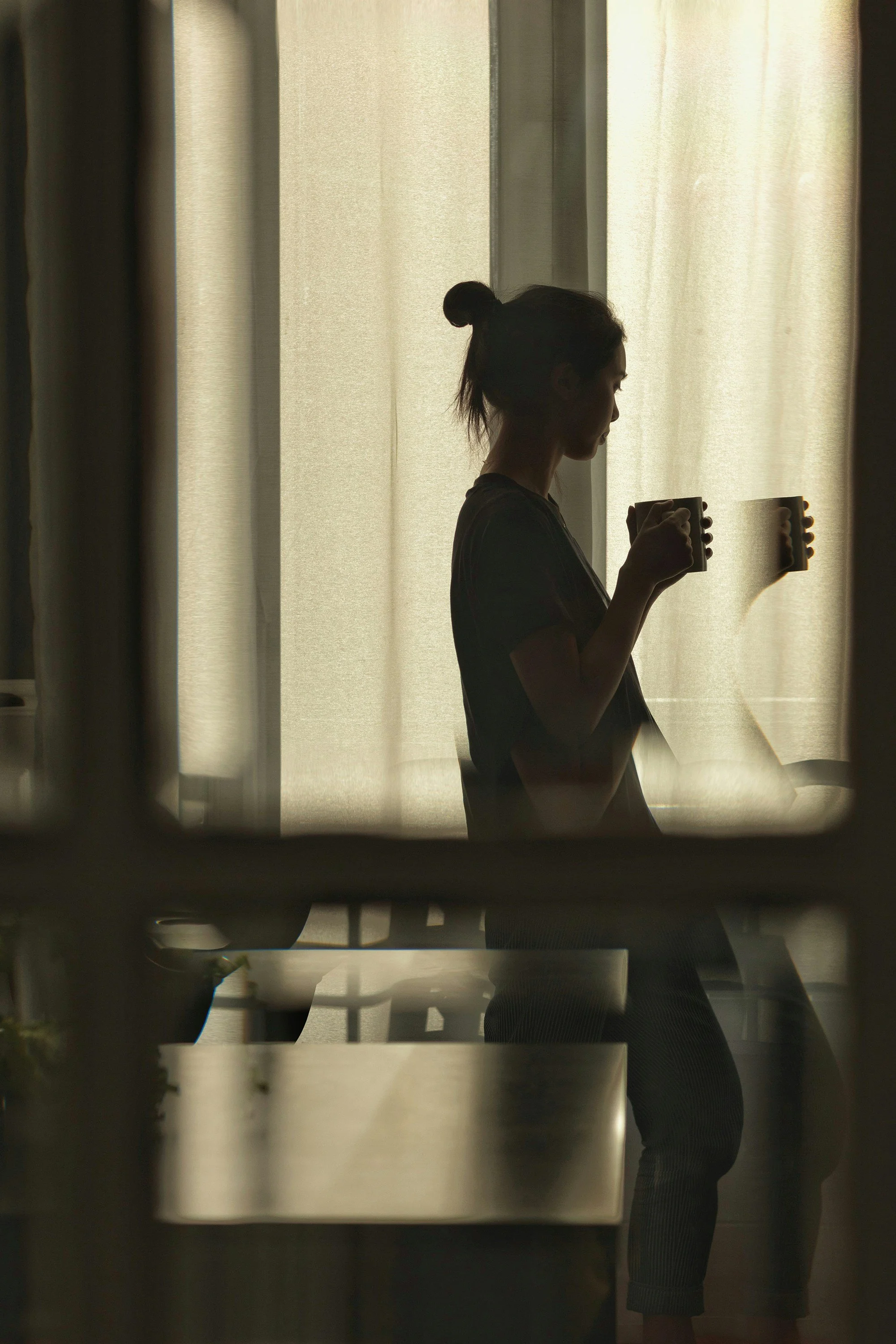 Adult taking a quiet moment to rest by a window, representing recovery from chronic stress and burnout through virtual therapy in North Carolina.