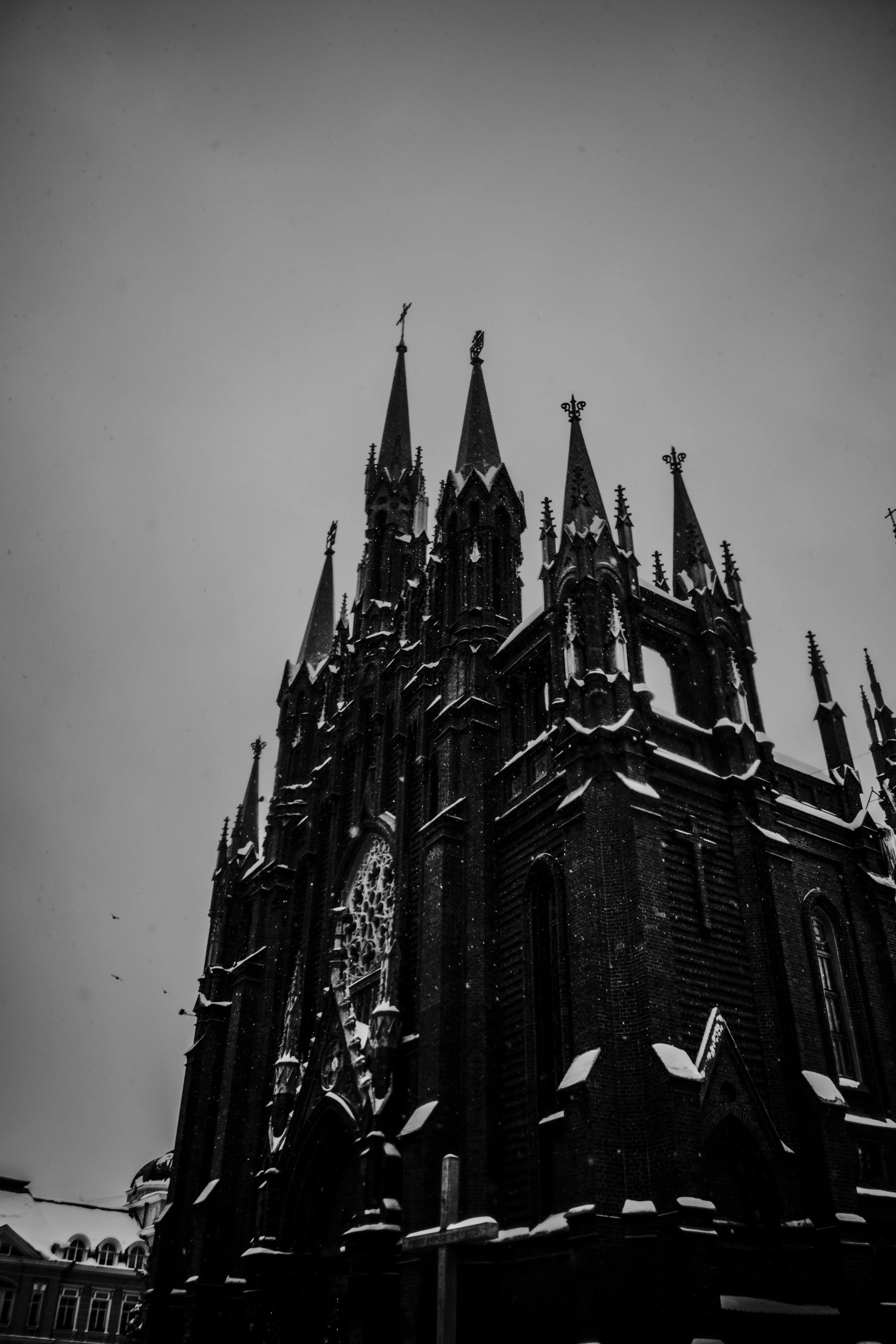 A black and white photo of a Gothic-style cathedral with tall spires, some topped with crosses, shrouded in fog.