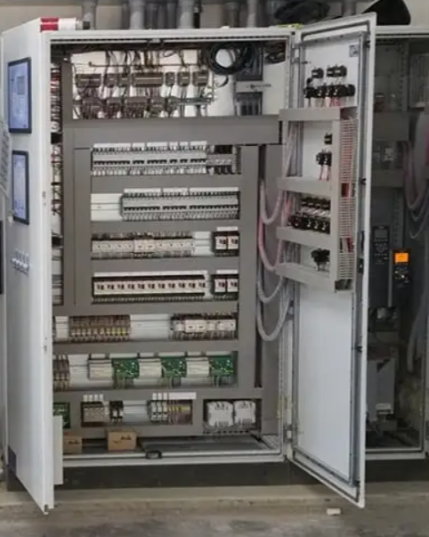 Open electrical control panel with various switches, relays, and wiring.