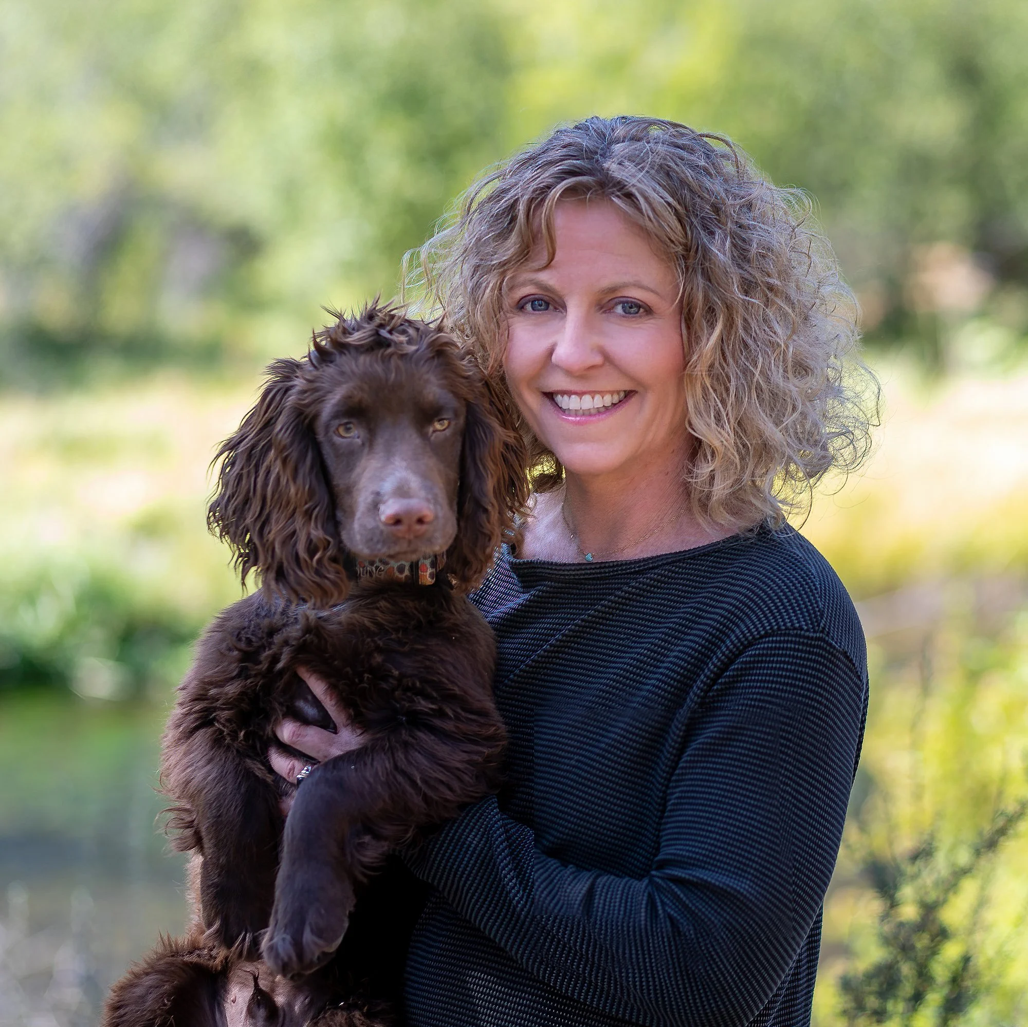 Real estate agent in Sisters Oregon from Stellar Realty with her dog by the Metolius River at outdoor session