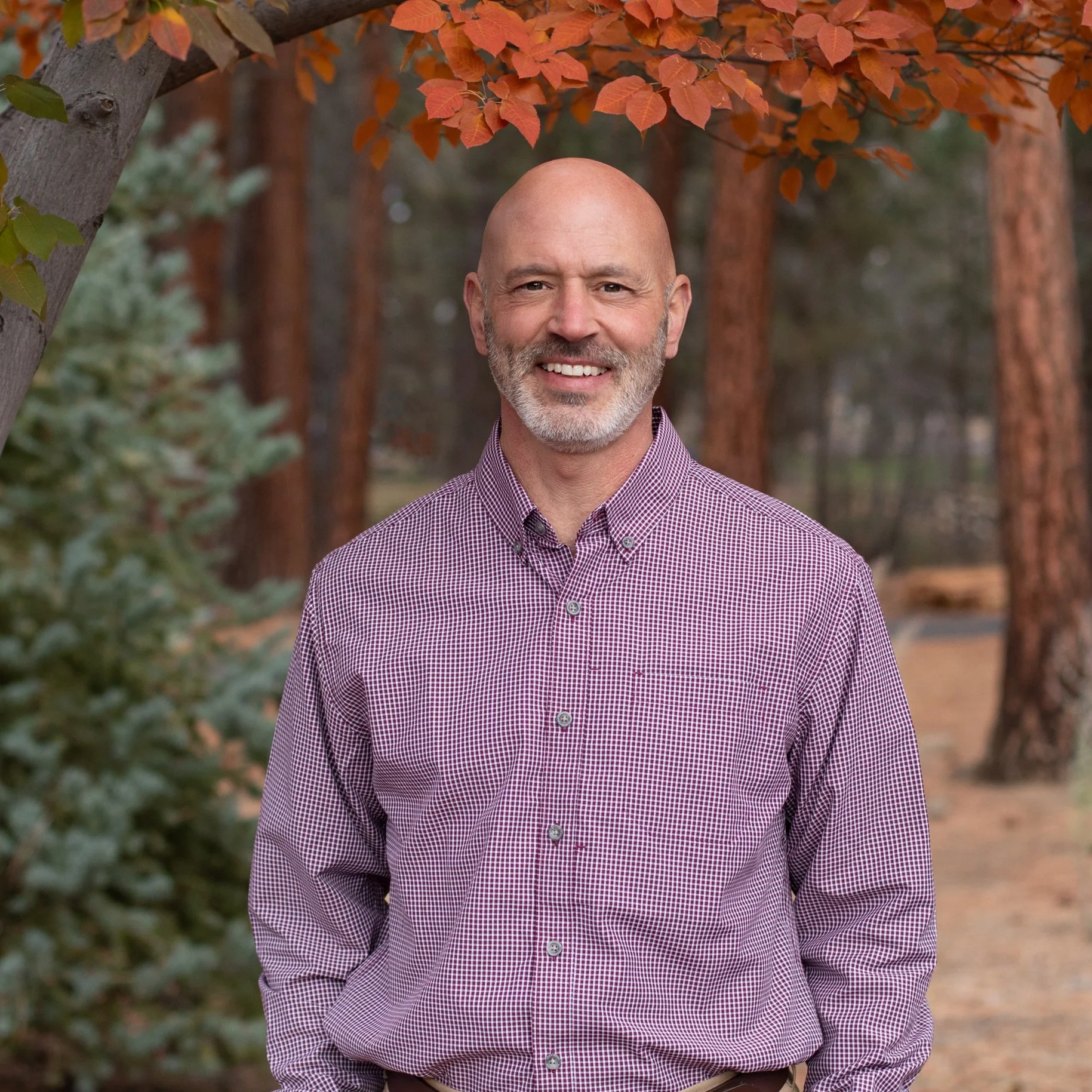 Professional headshot of real estate broker in Sisters Oregon with outdoor background and approachable expression