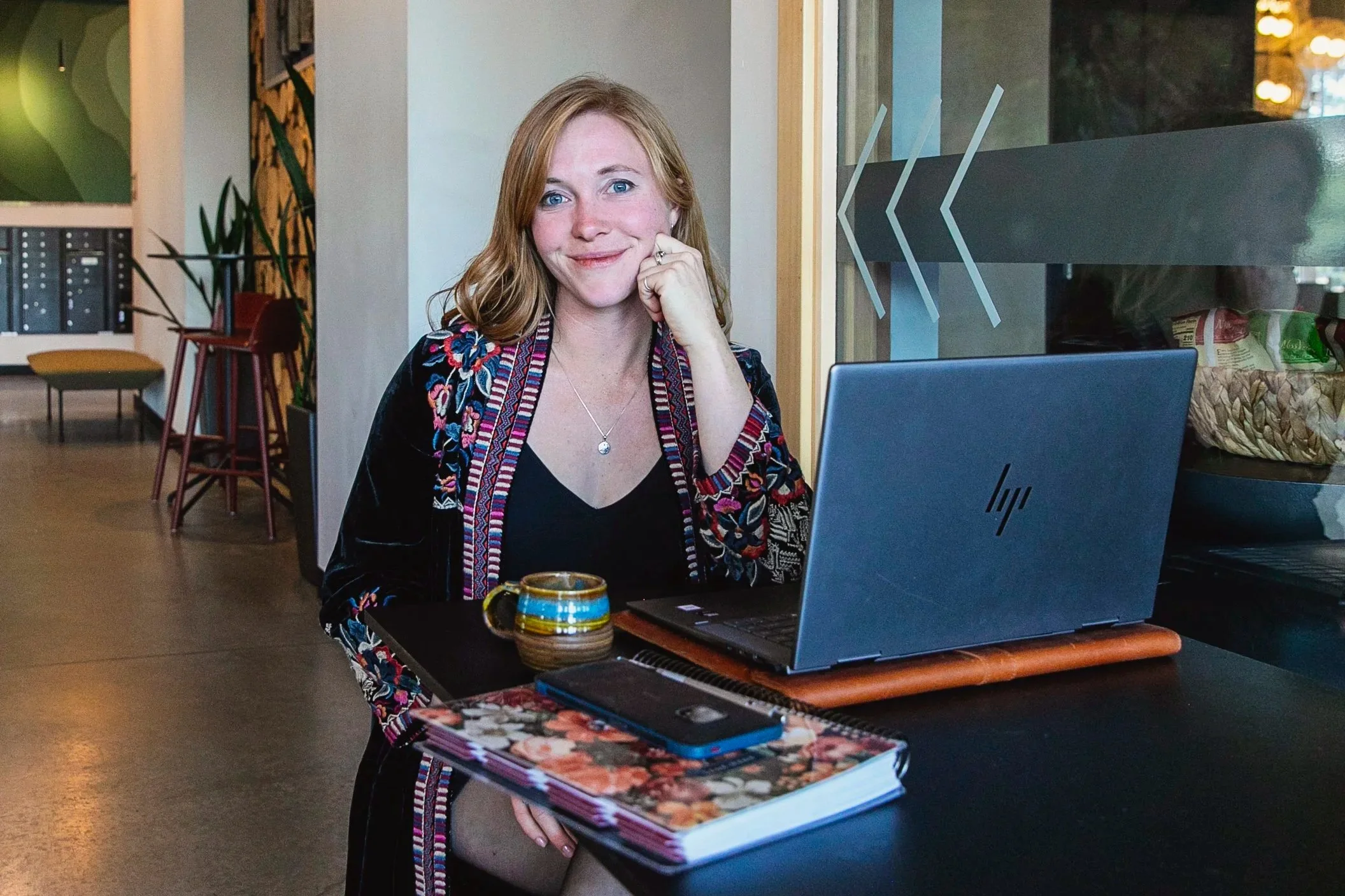 Savage Skye Designs owner working with laptop and coffee creating soulful logo and website designs