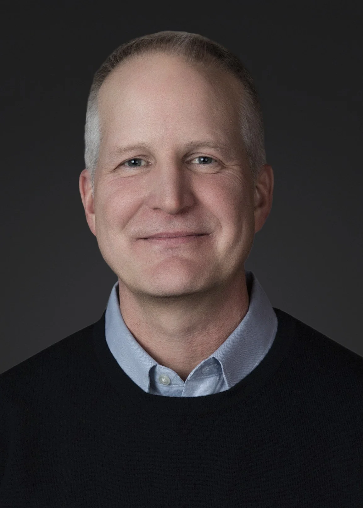 Clean studio style board member headshot of male executive with neutral background