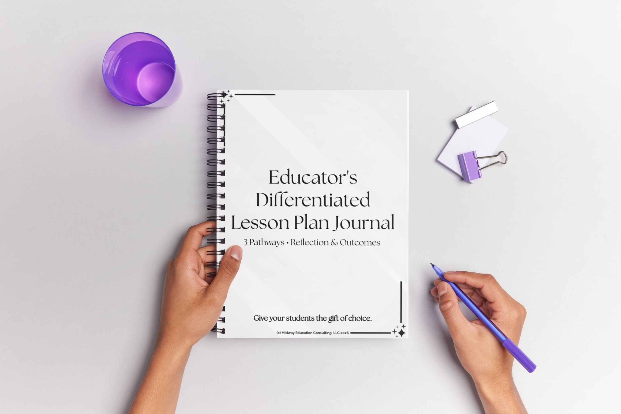 A person holding a spiral-bound notebook labeled 'Educator's Differentiated Lesson Plan Journal' on a white background. One hand is holding the notebook, and the other is writing with a blue pen. Items on the table include a purple cup, a white binder clip, paper notes, and a purple highlighter.