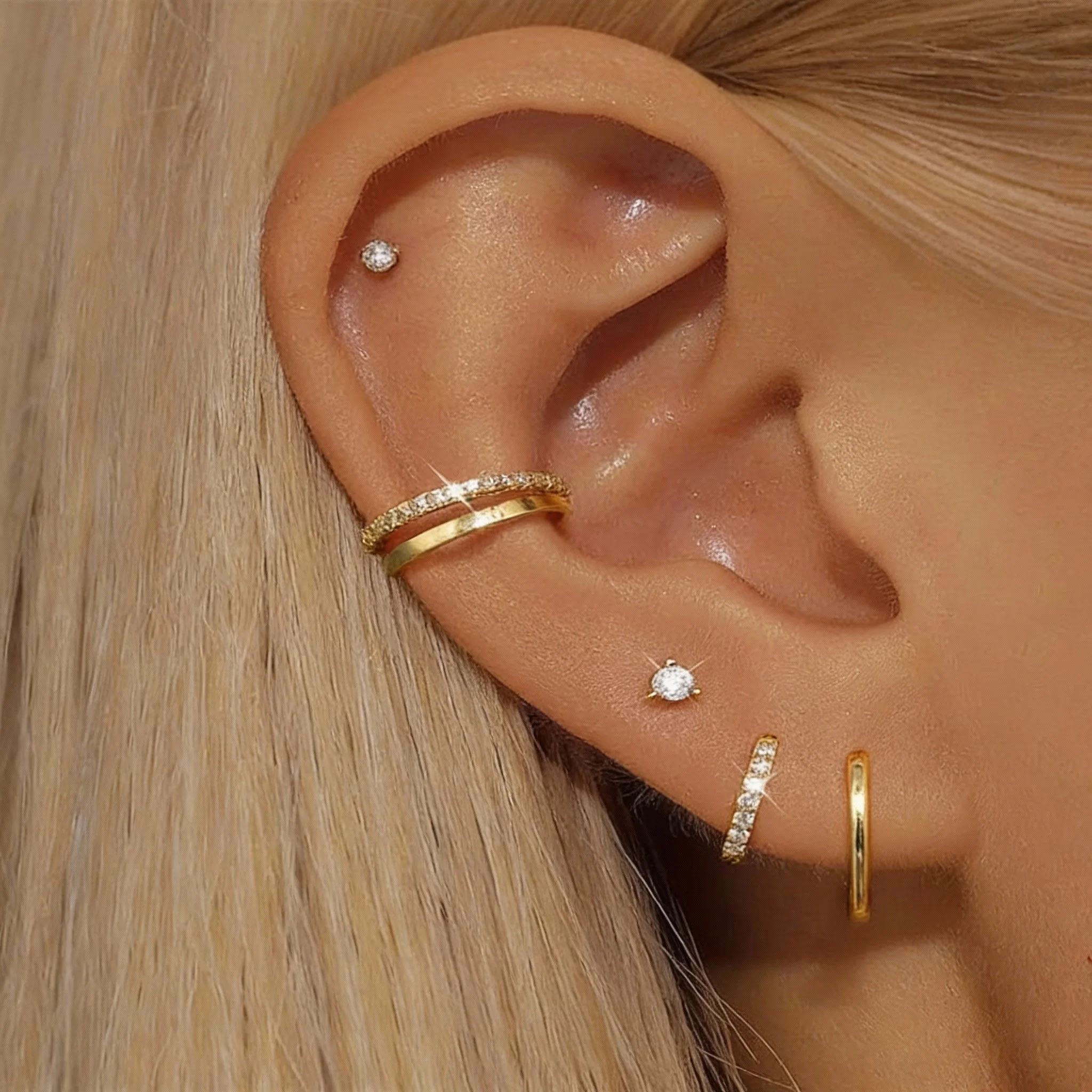 Close-up of curated ear piercings with gold hoops and diamond studs, professionally placed by expert body piercers at Salvation Tattoo Lounge