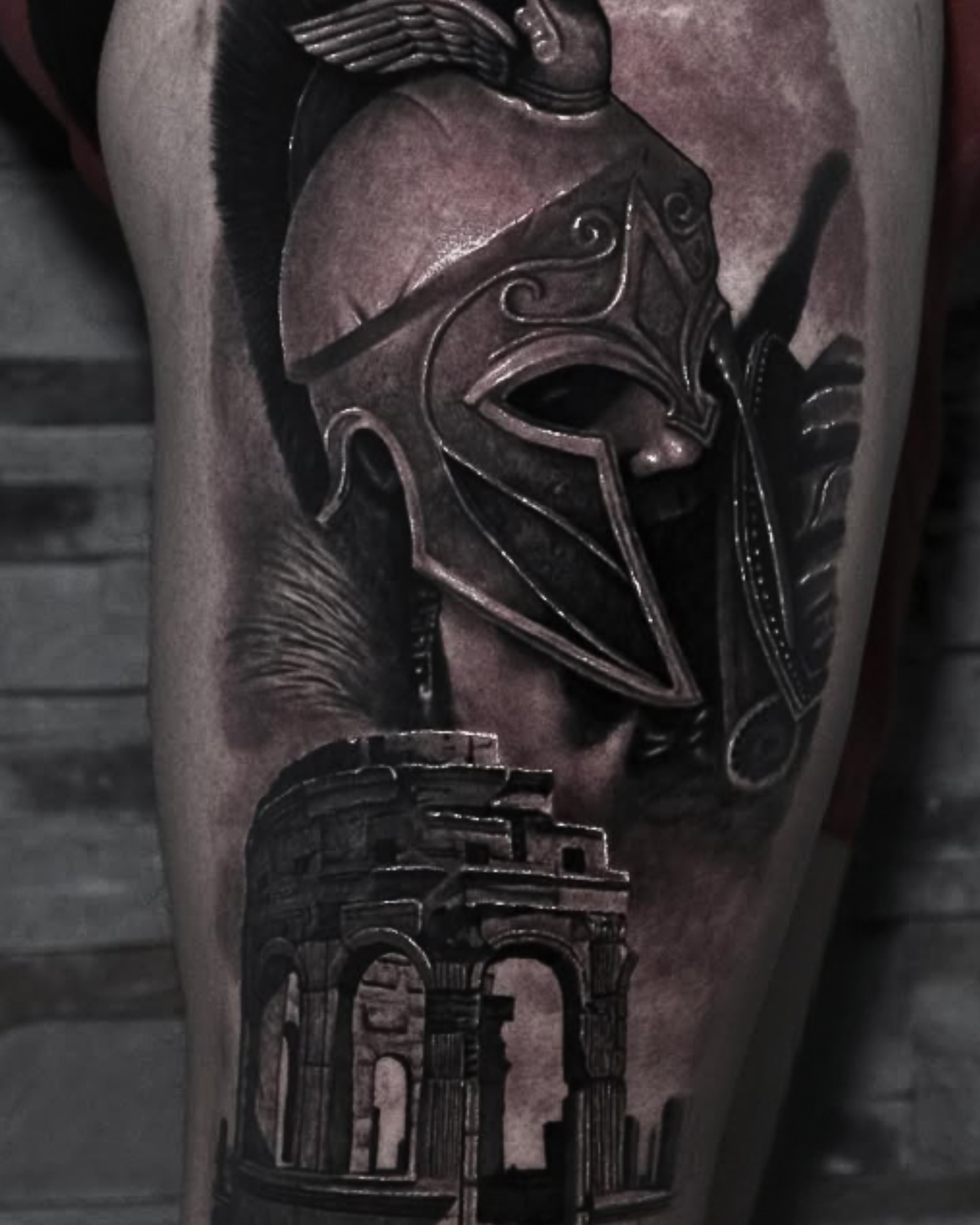 Black and grey realism tattoo featuring a detailed Spartan helmet and ancient Roman architecture, realistic tattoo work by a Miami Beach tattoo artist