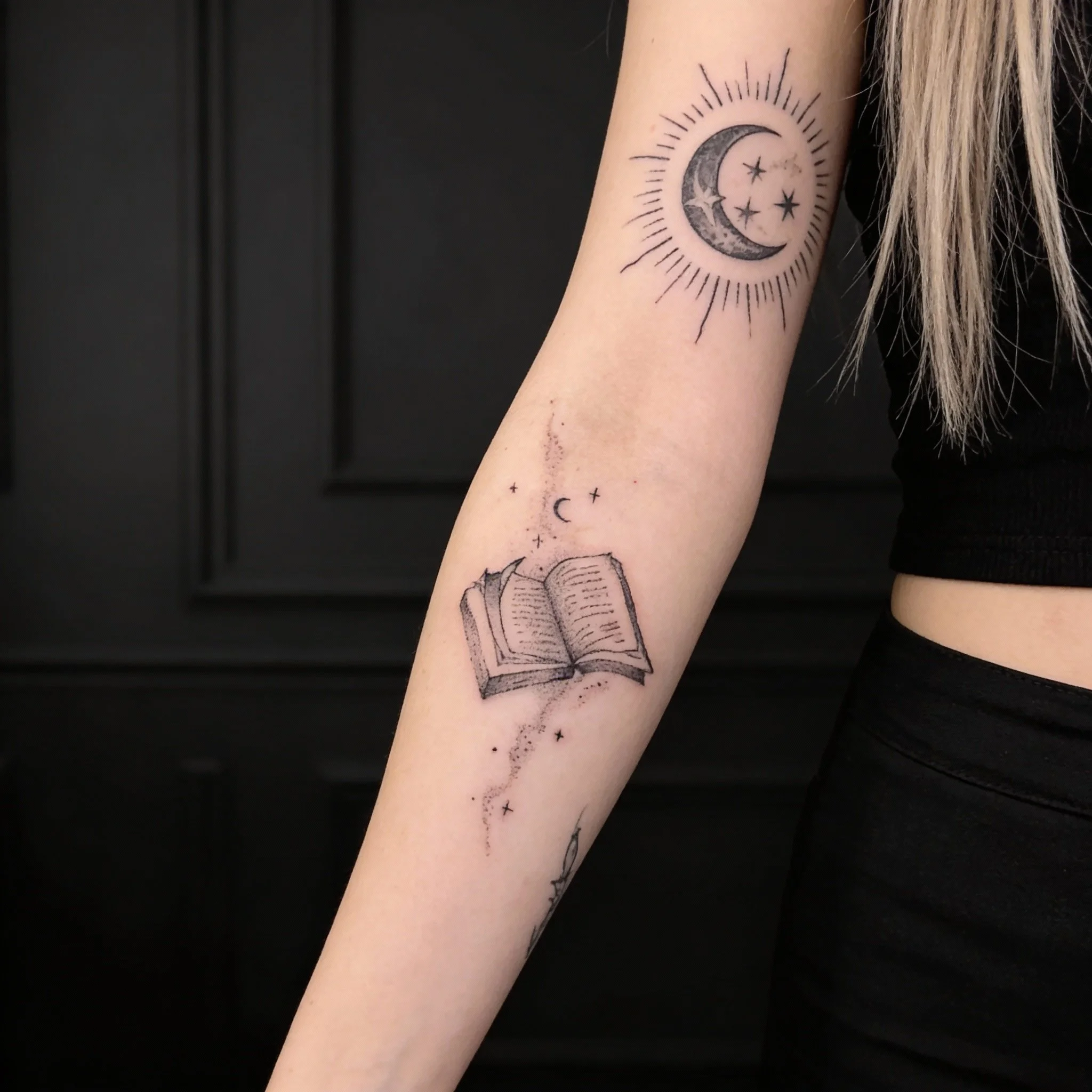 Fine line black ink tattoo on the forearm featuring a minimalist illustrative design