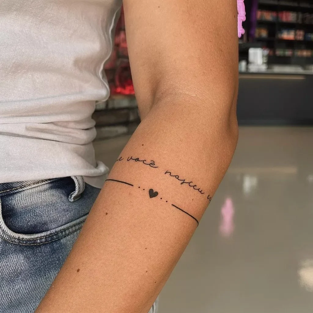 Minimalist linework armband tattoo with small script and simple geometric details