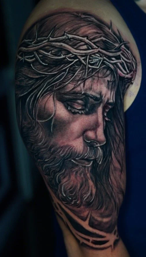 Black and gray Jesus portrait tattoo with crown of thorns by Axel at Salvation Tattoo Lounge in Coral Springs