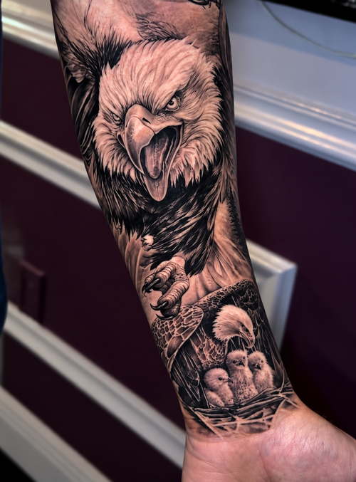 Black and grey bald eagle and nestlings forearm tattoo by Ajay