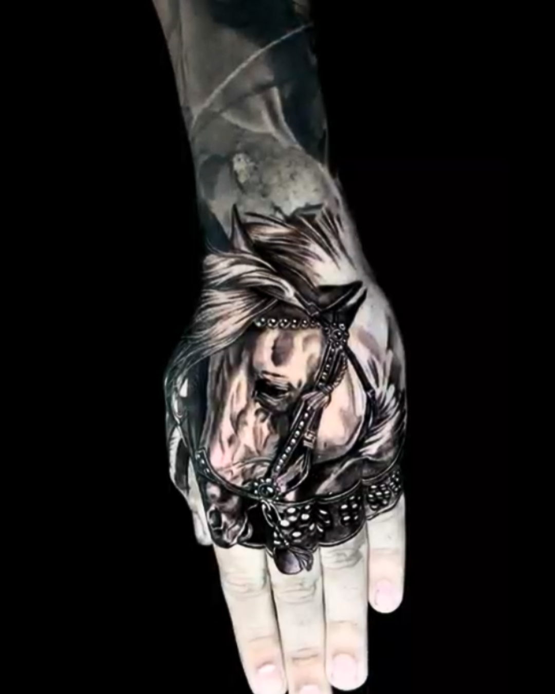 Black and gray realism hand tattoo featuring a detailed horse portrait with flowing hair and ornamental shading.