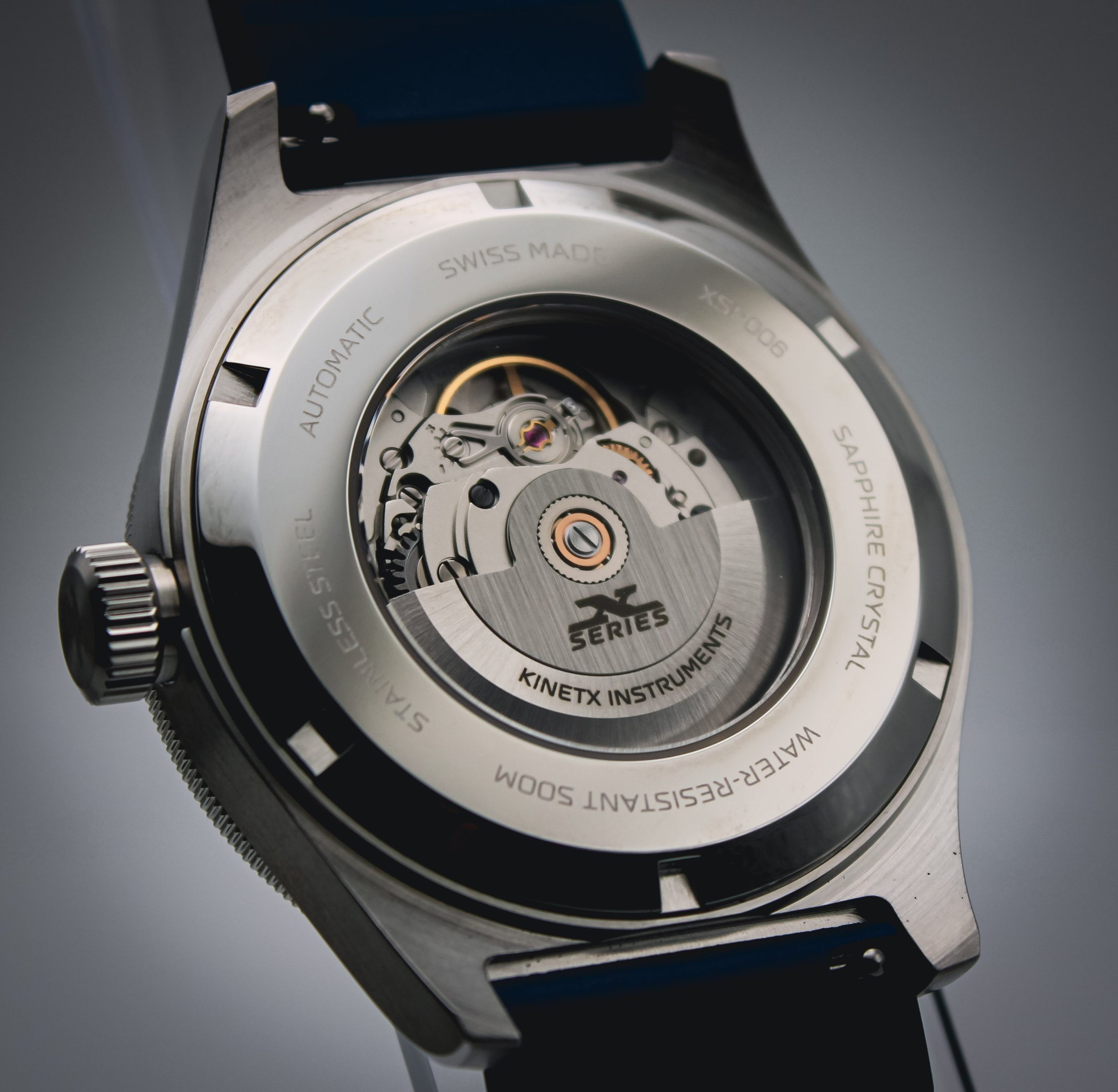 Close-up of a mechanical watch movement with gears and components, featuring a polished metal finish.