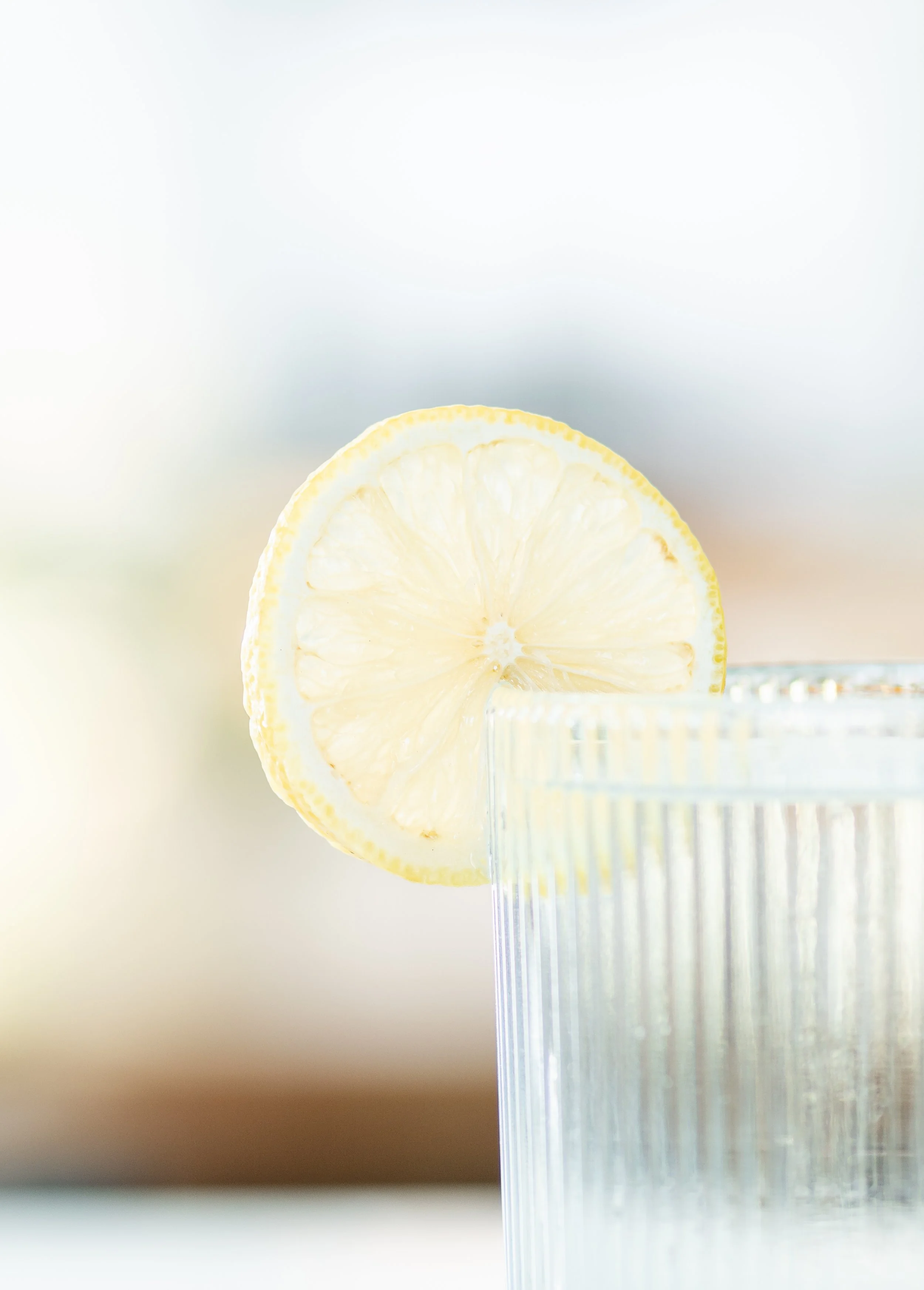 Close-up of a glass with a slice of lemon on its rim, with a blurred background.