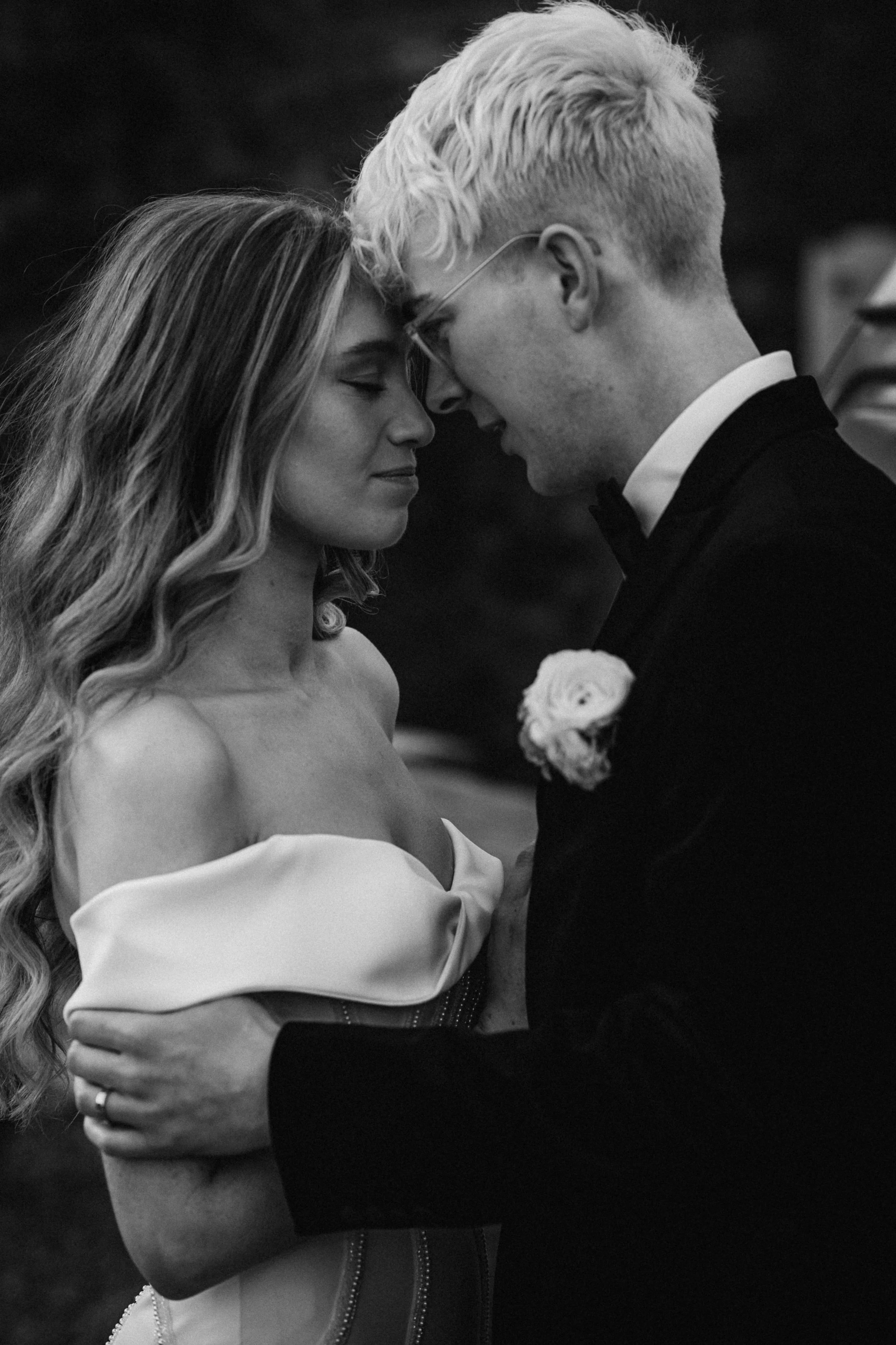 Black and white photo of a couple embracing, bride wearing wedding dress.