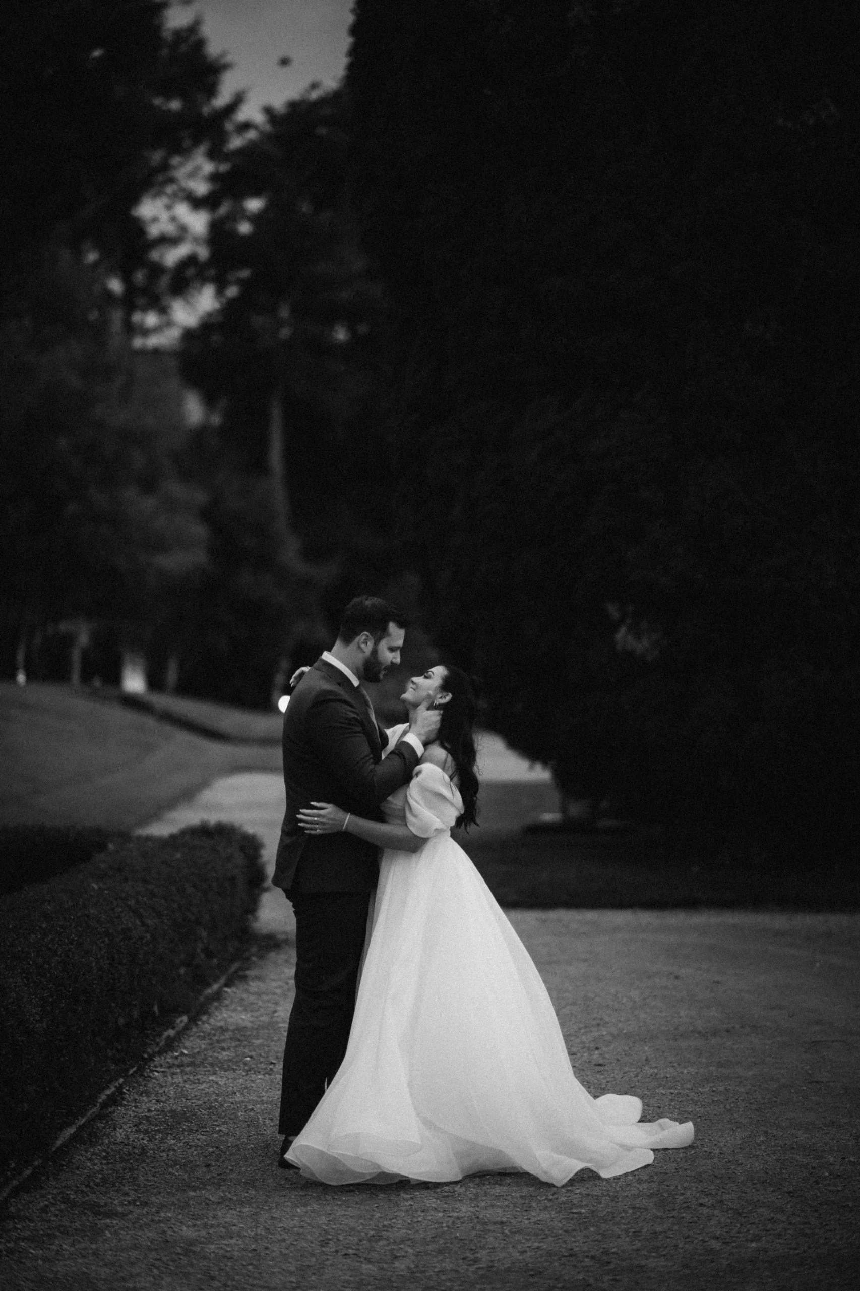 Couple embracing outdoors, woman in wedding dress, black and white photo