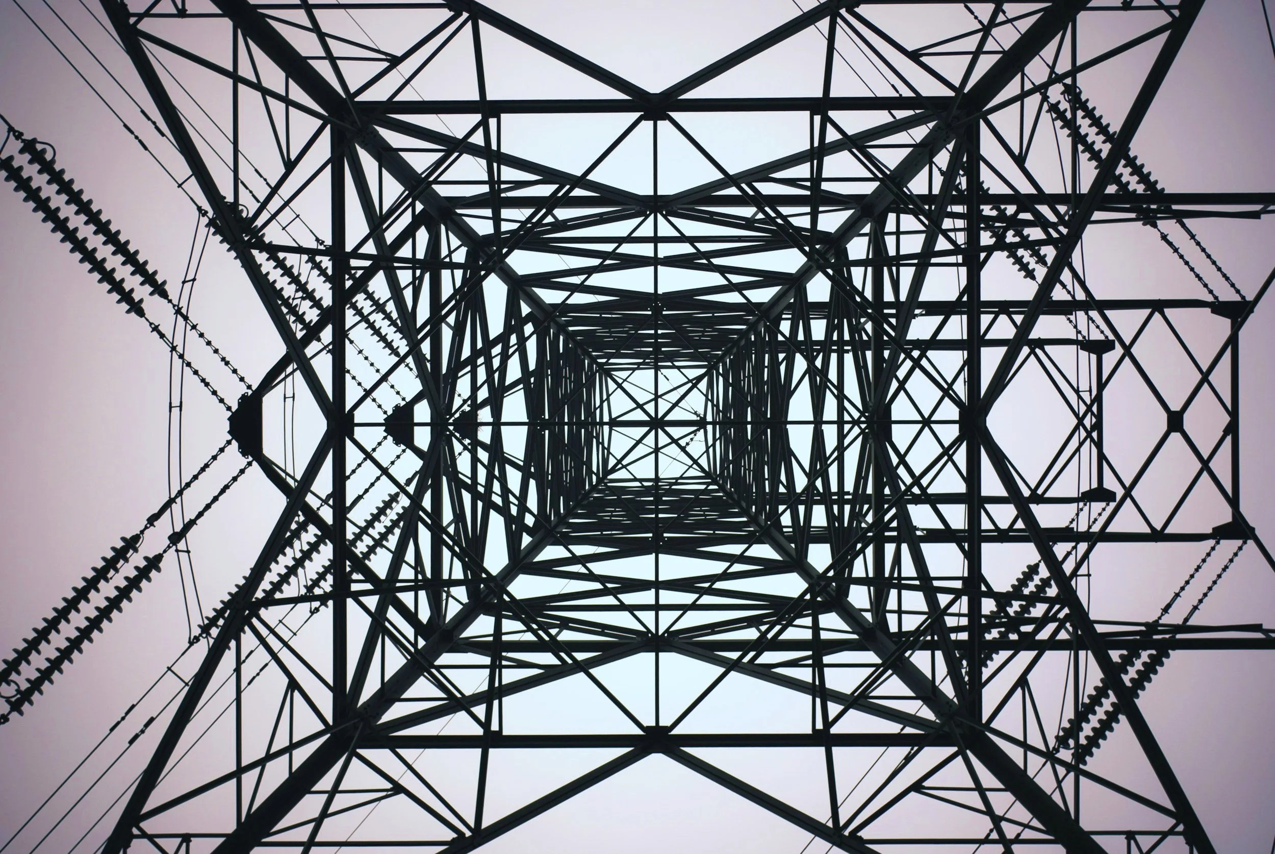 View from beneath an electricity pylon, revealing intricate steel lattice structure.