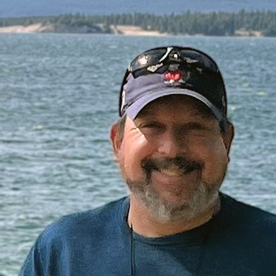 Man in blue shirt standing in front of a large body of water