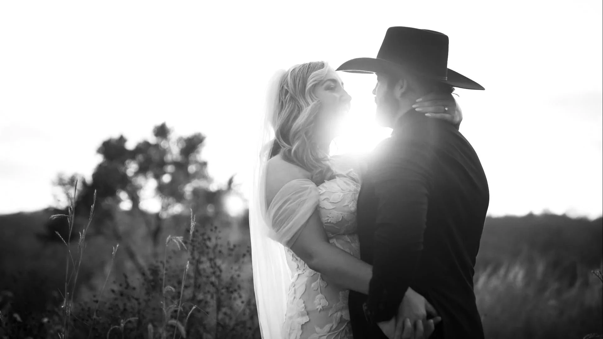 bride and groom embrace in field