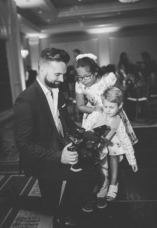 Wedding videographer showing children camera