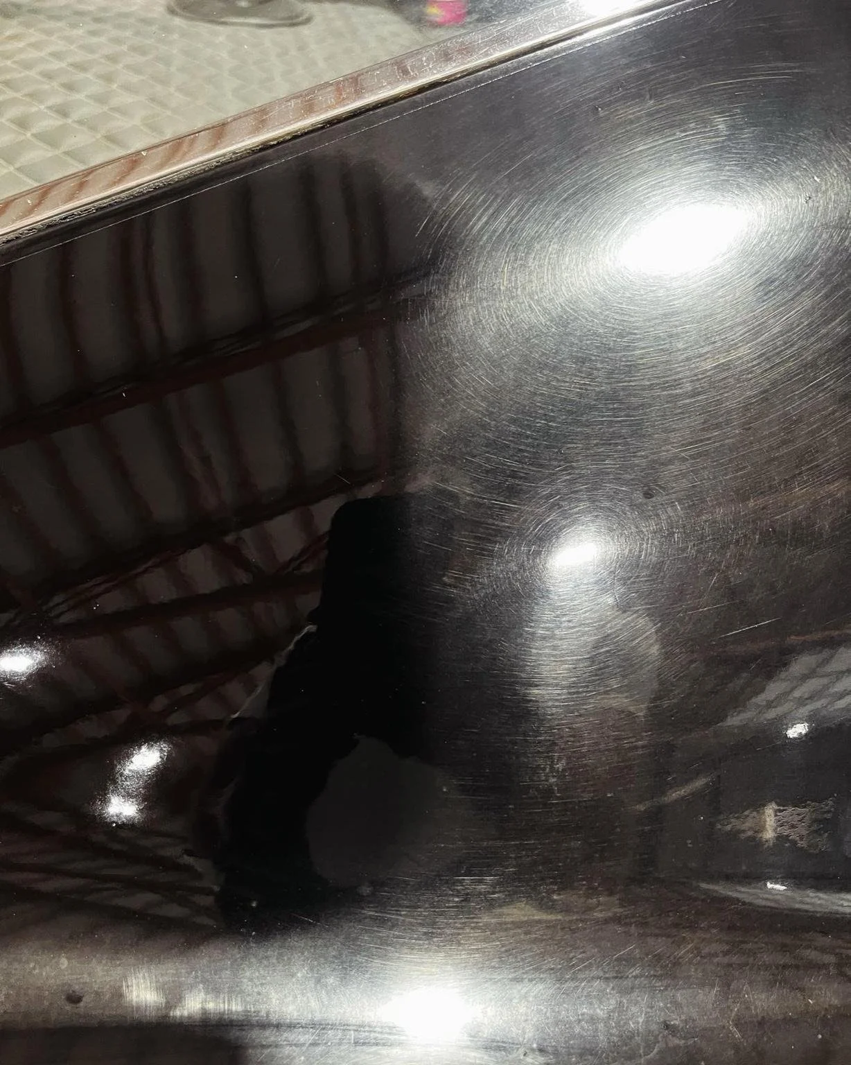 Side-by-side comparison of a black car hood before and after paint correction - right side with swirl marks, left side restored to a glossy finish by Bryanz Auto Detailing.