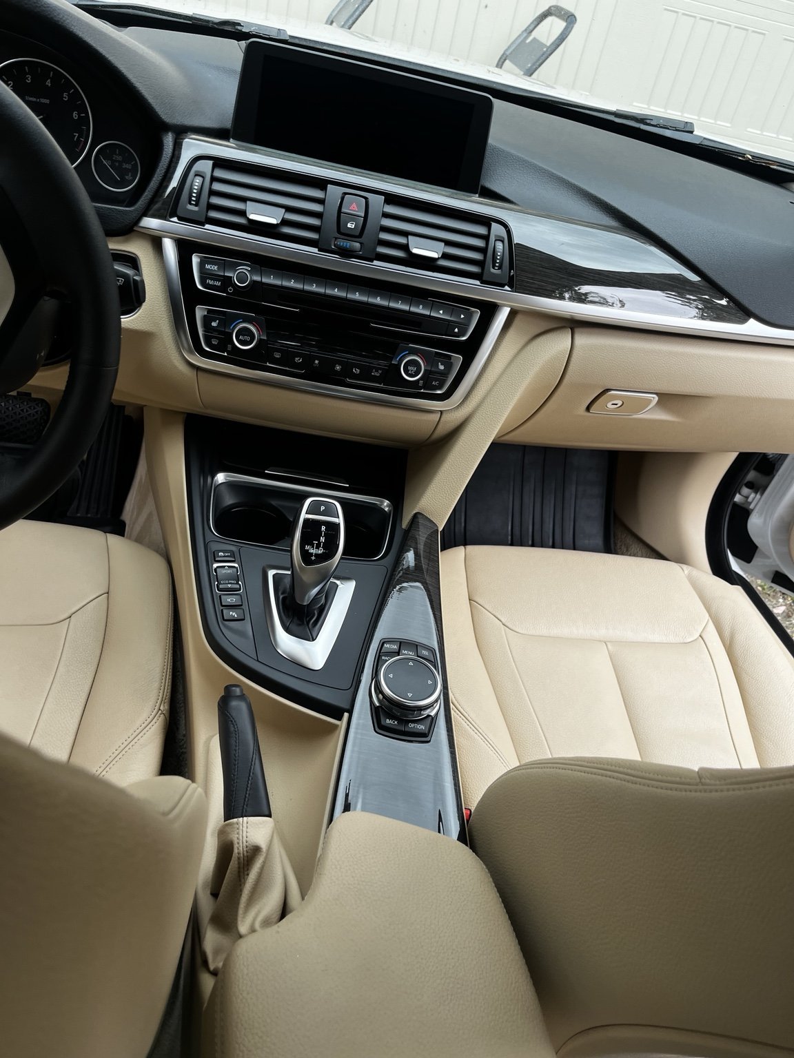 Clean BMW beige leather interior and center console after professional detailing by Bryanz Auto Detailing