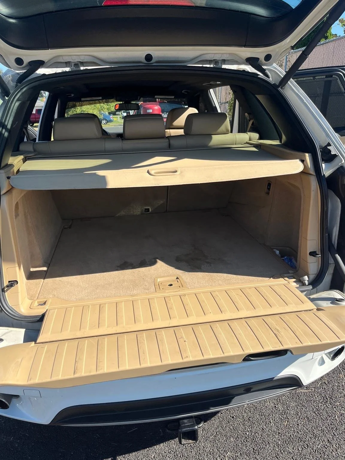 Before interior trunk detailing on a BMW SUV showing heavy carpet stains and dirt buildup before deep cleaning service.
