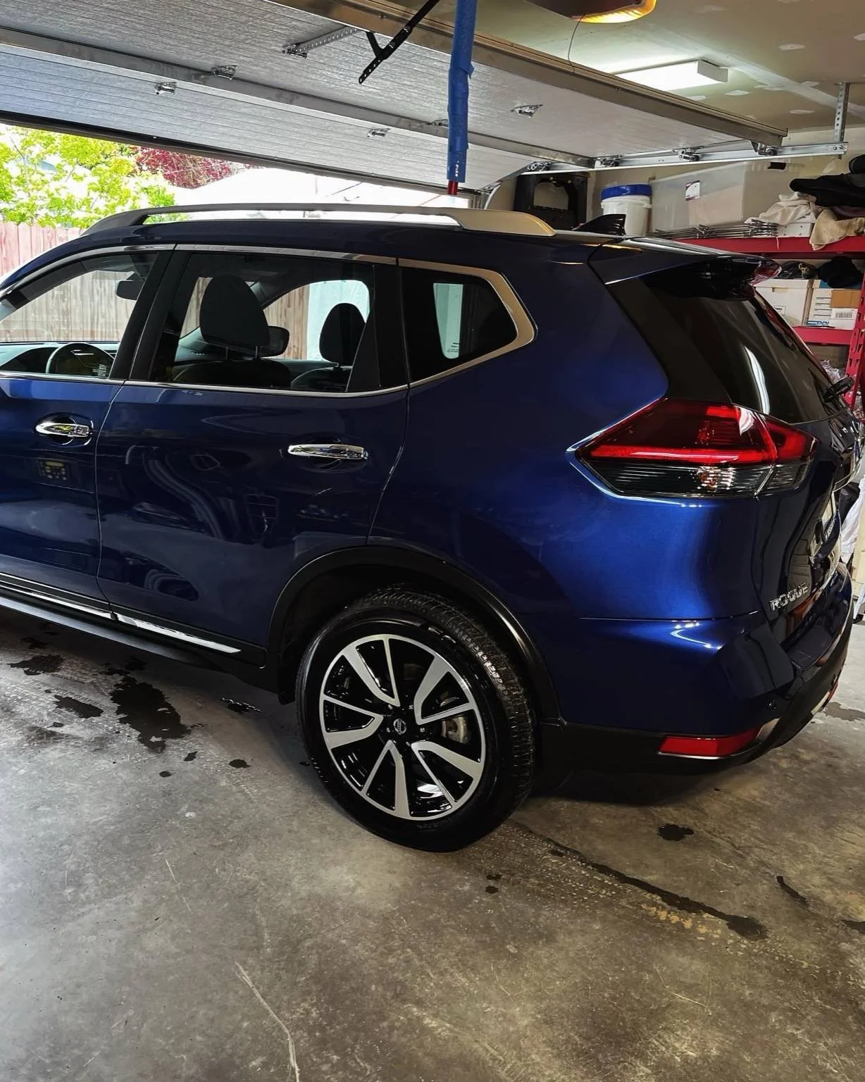 Blue Nissan Rogue after paint correction and detailing by Bryanz Auto Detailing, showing a flawless finish and tire shine in the garage.